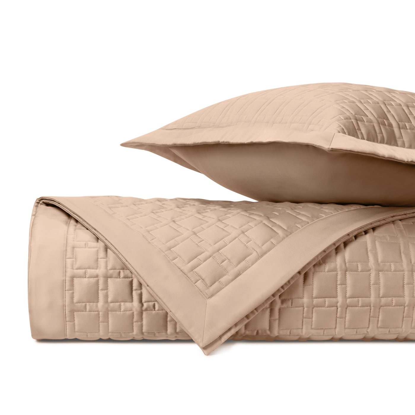 Folded champagne quilted coverlet and sham showing square grid stitching pattern.