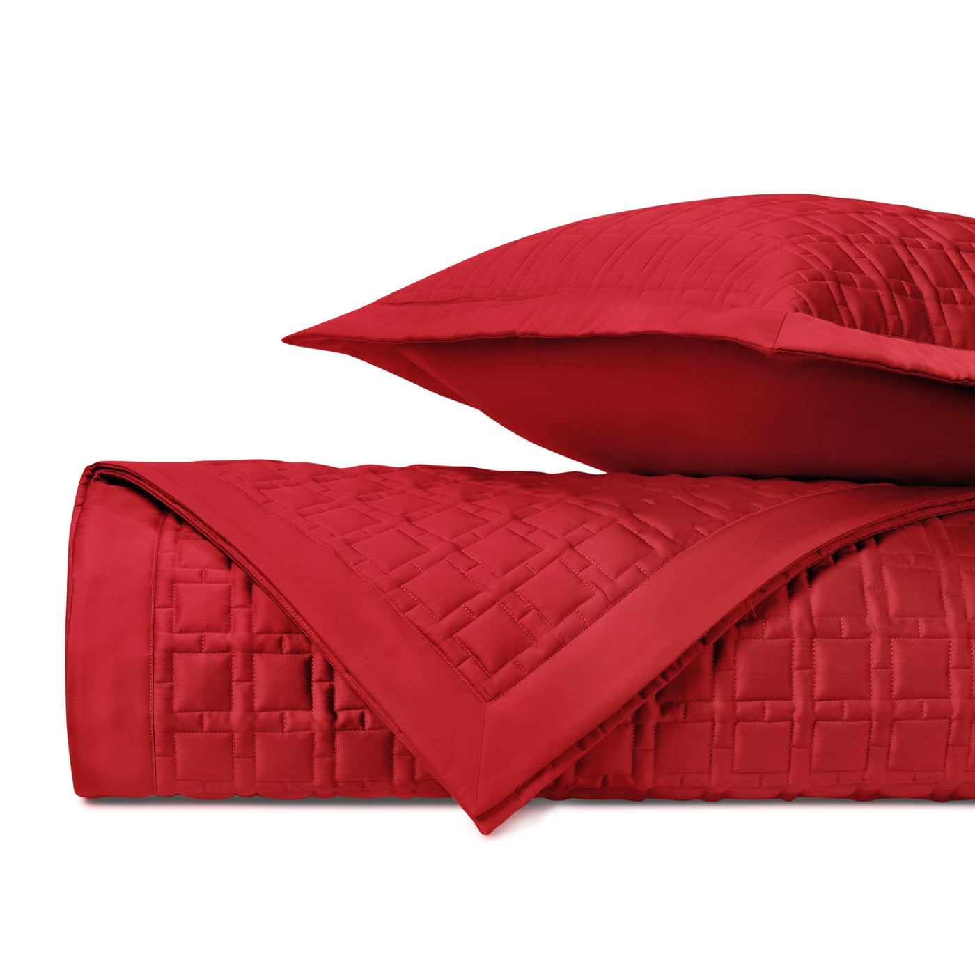 Close-up of crimson quilted square-stitch texture on rolled coverlet with sham.