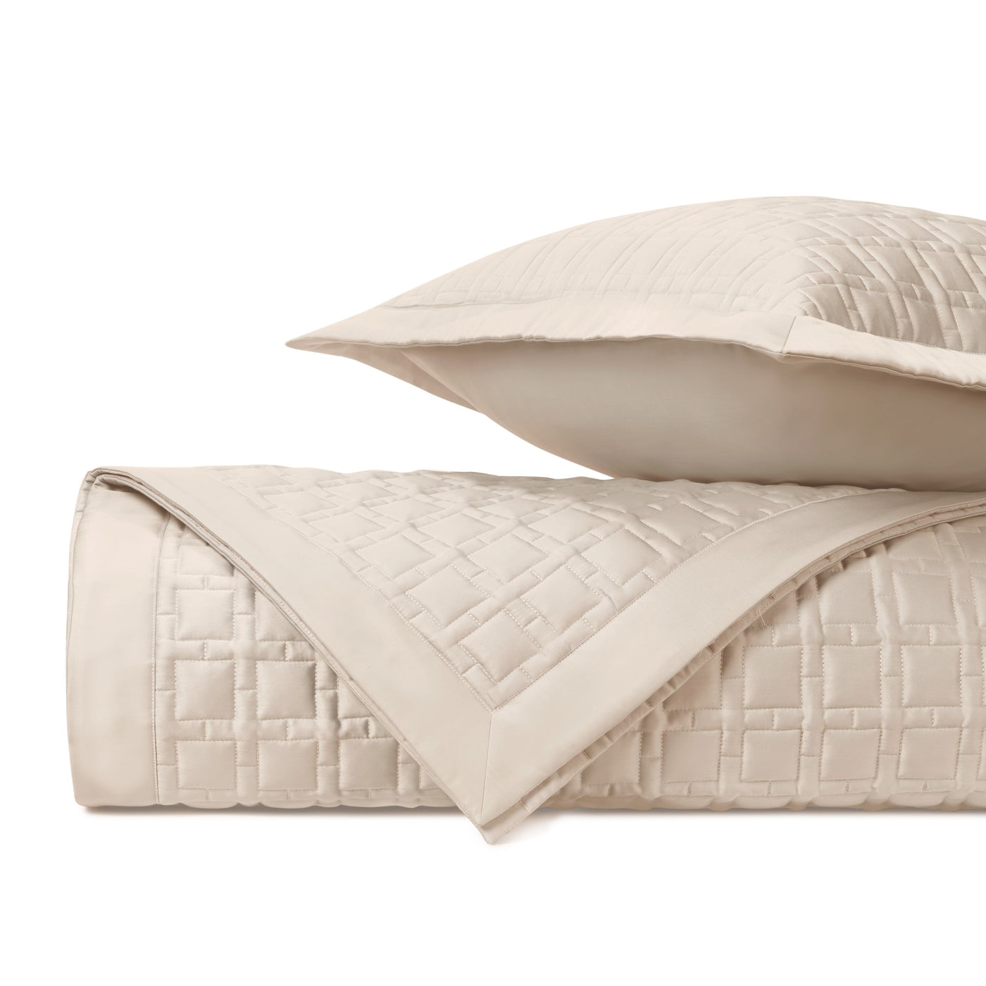 Close-up of ivory quilted square-pattern coverlet and sham, rolled and stacked.