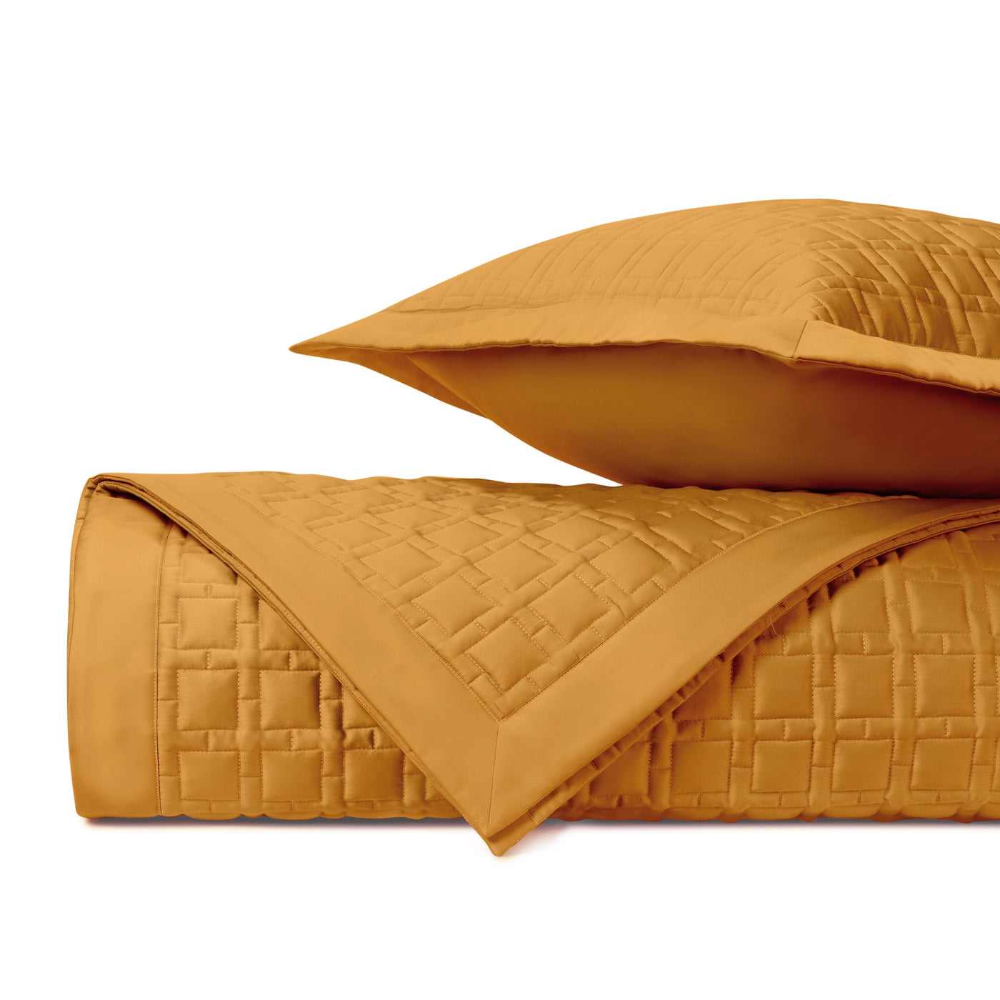 Close-up of saffron quilted cotton coverlet and sham showing square stitching pattern.