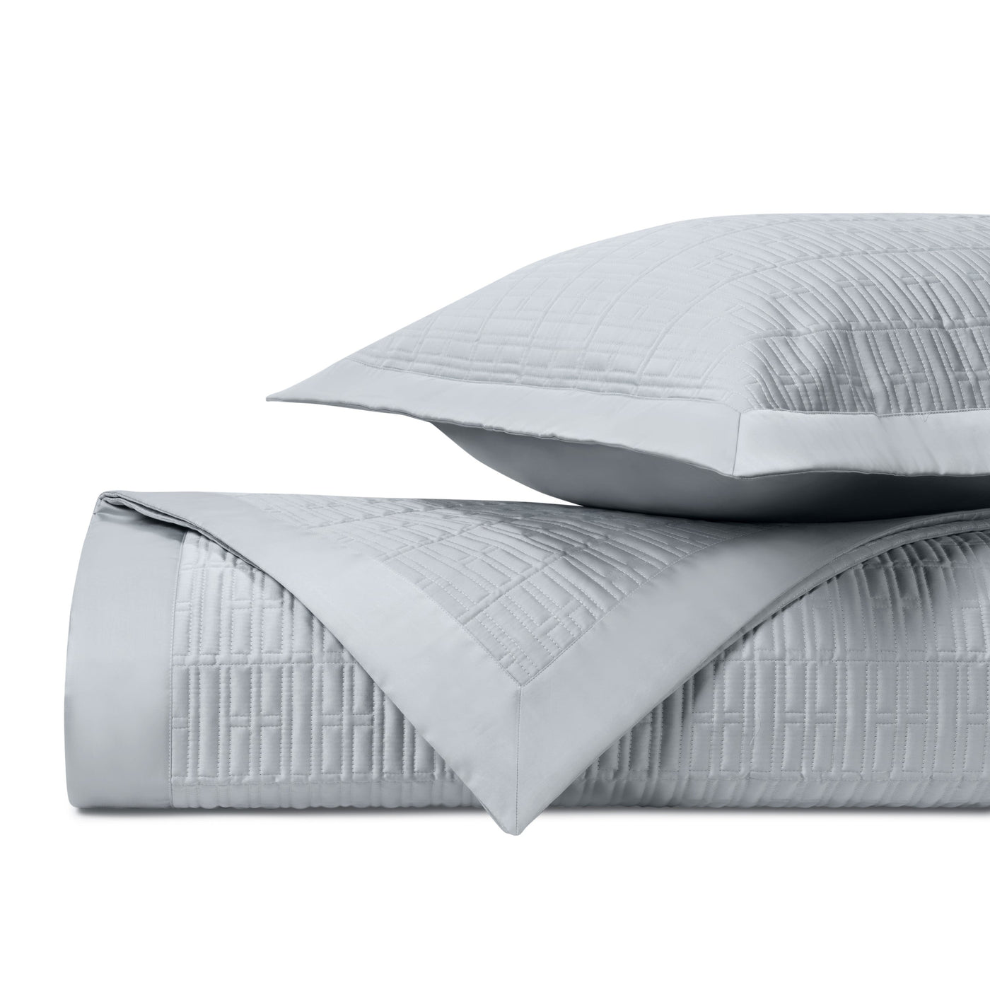 Close-up of silver quilted coverlet and sham showing geometric stitched grid pattern.