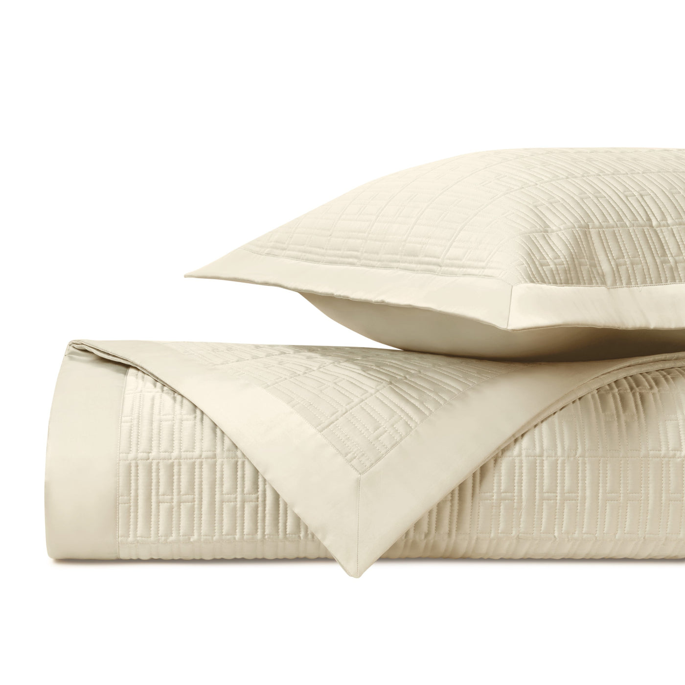 Close-up of ivory quilted coverlet and sham showing geometric grid stitching pattern.