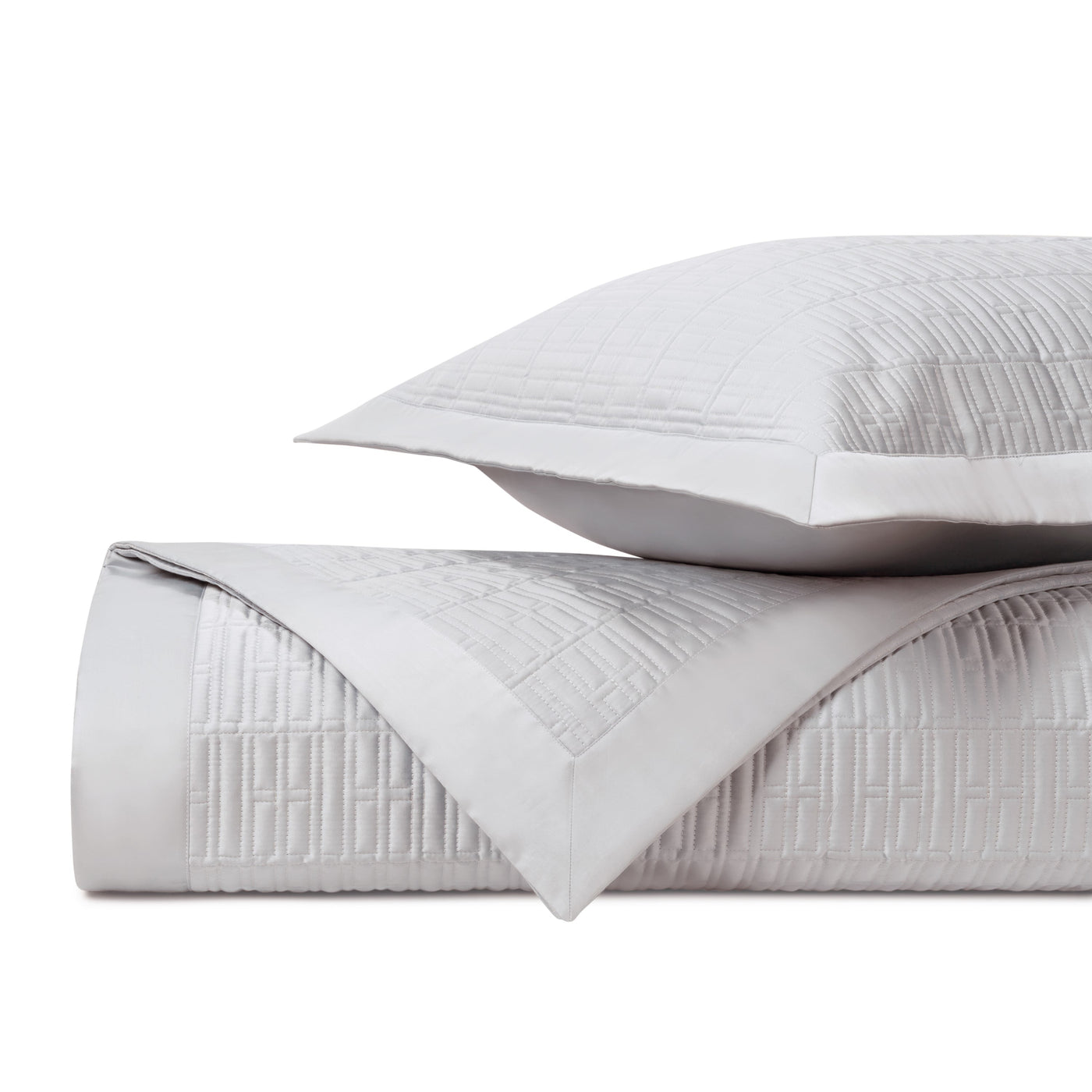 Close-up of pearl white quilted coverlet and sham with geometric square stitching pattern.