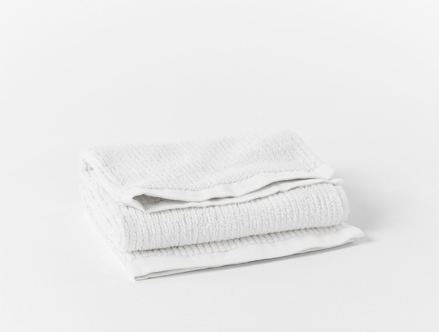 Coyuchi Temescal Ribbed hand towel folded, showing ribbed texture in white.