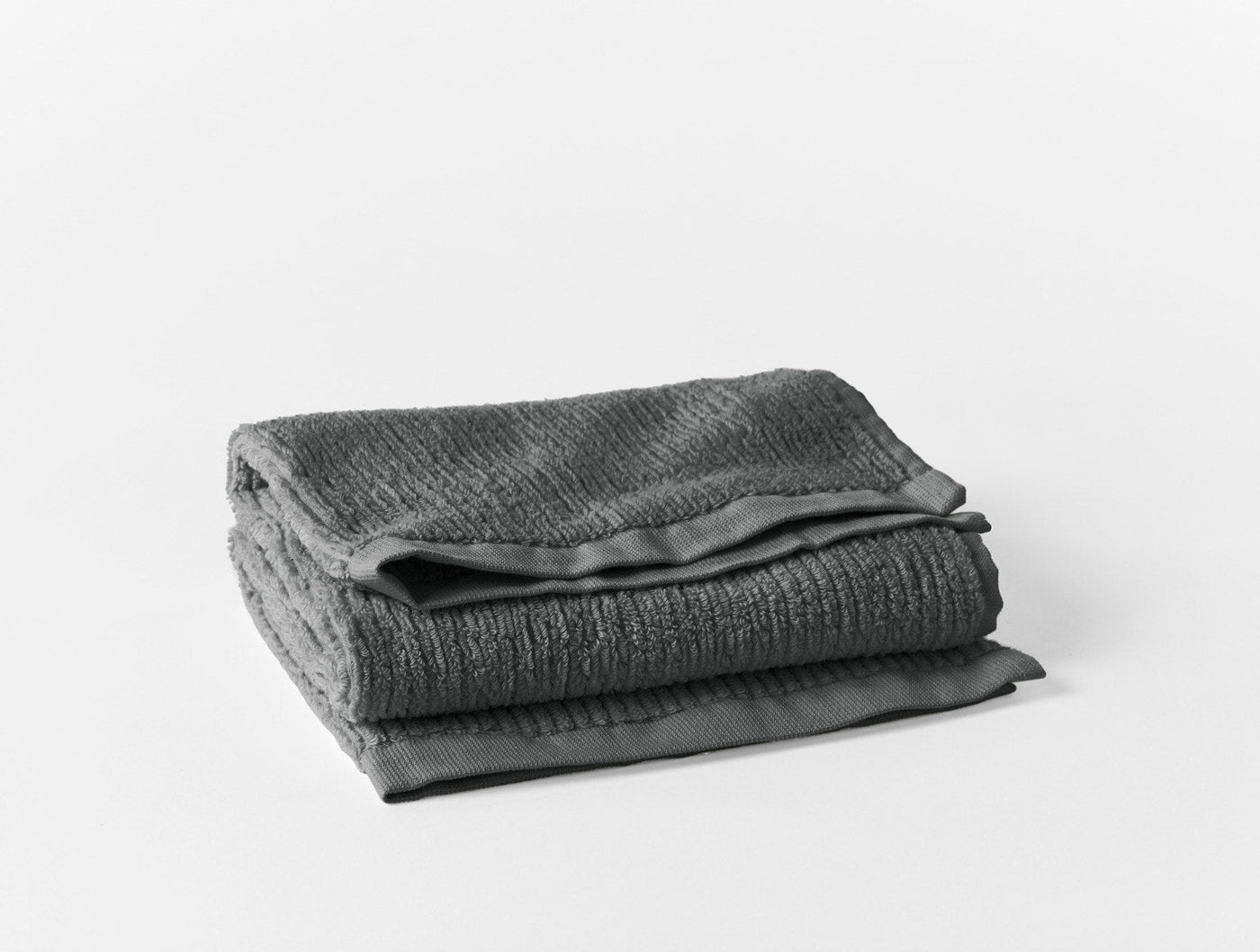 Folded charcoal ribbed towel set showing textured weave and smooth satin trim detail.