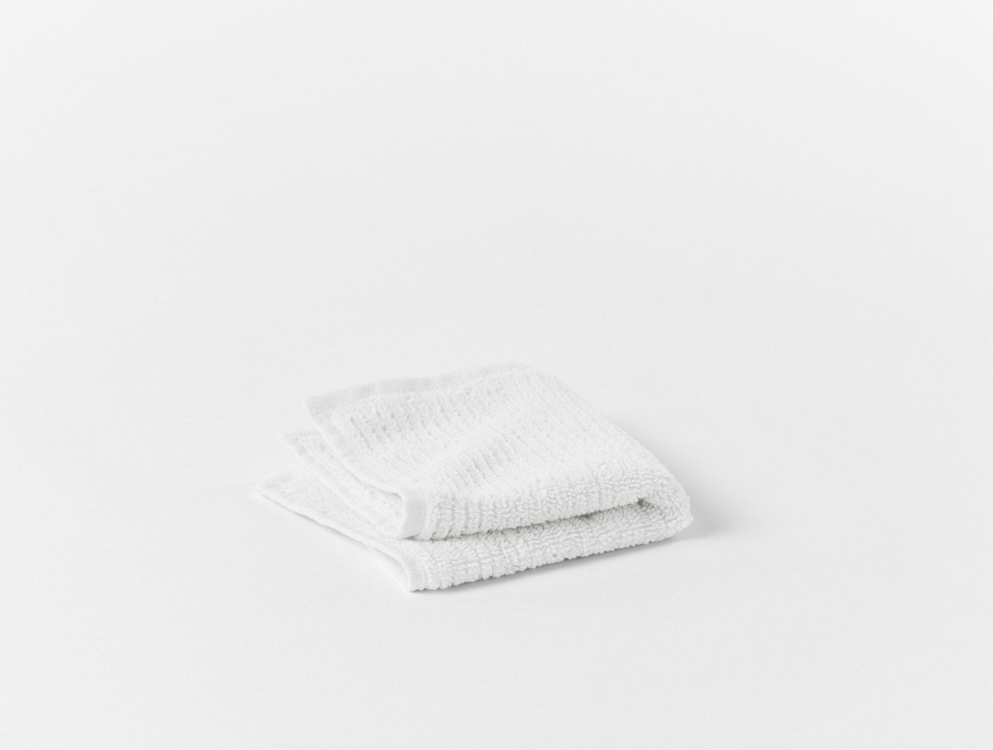 Coyuchi Temescal Ribbed wash cloth in white, folded flat against white background.