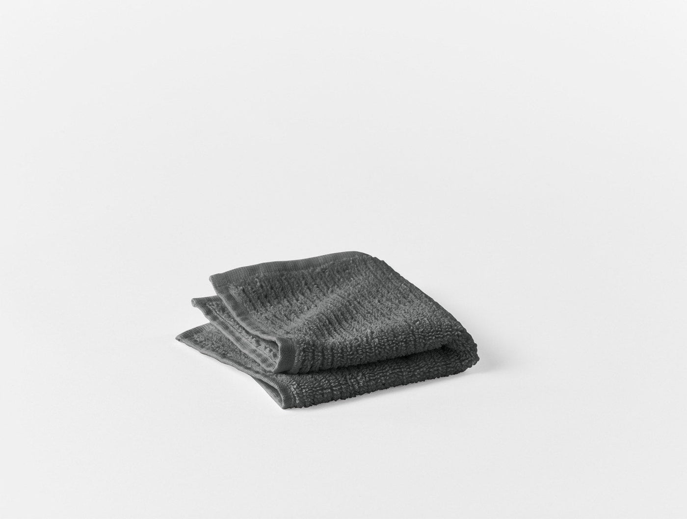 Close-up of folded charcoal ribbed Coyuchi Temescal bath sheet on white background.