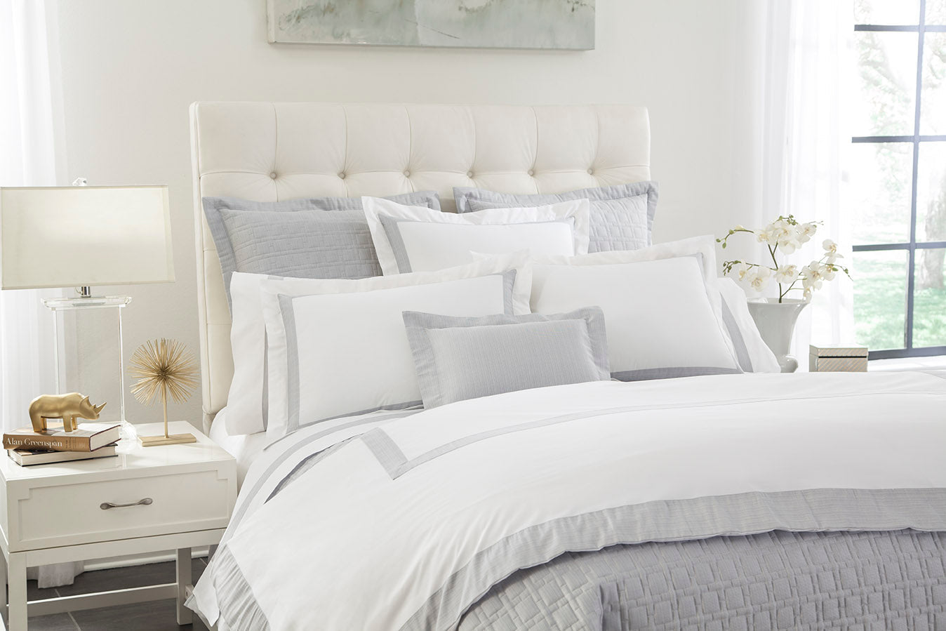 Bright bedroom styled with white and silver-grey Terra bedding, layered pillows, and duvet.