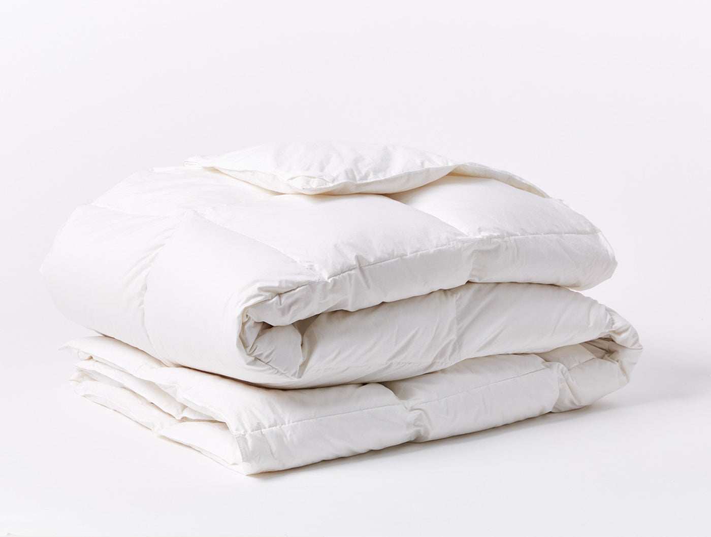 Coyuchi Three Season Down duvet insert in white, folded to show loft and quilted stitching.
