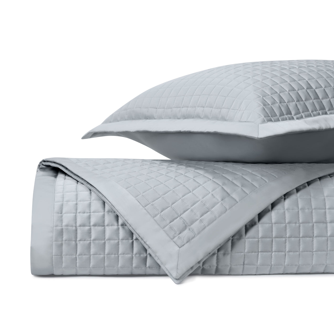 Close-up of silver quilted yardage with geometric square stitching pattern and border trim.