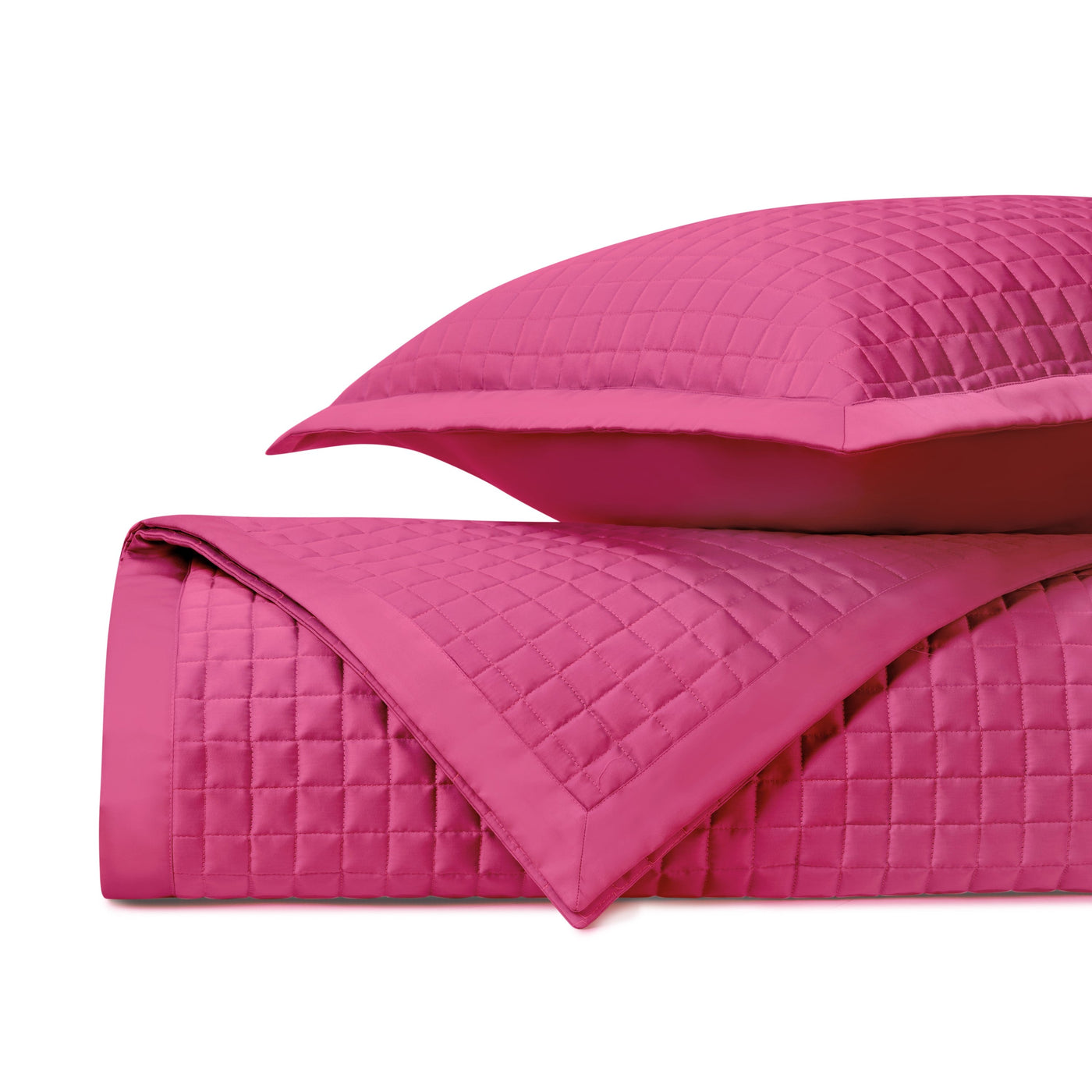 Fuchsia quilted cotton coverlet and sham folded, showing grid-stitched diamond pattern detail.