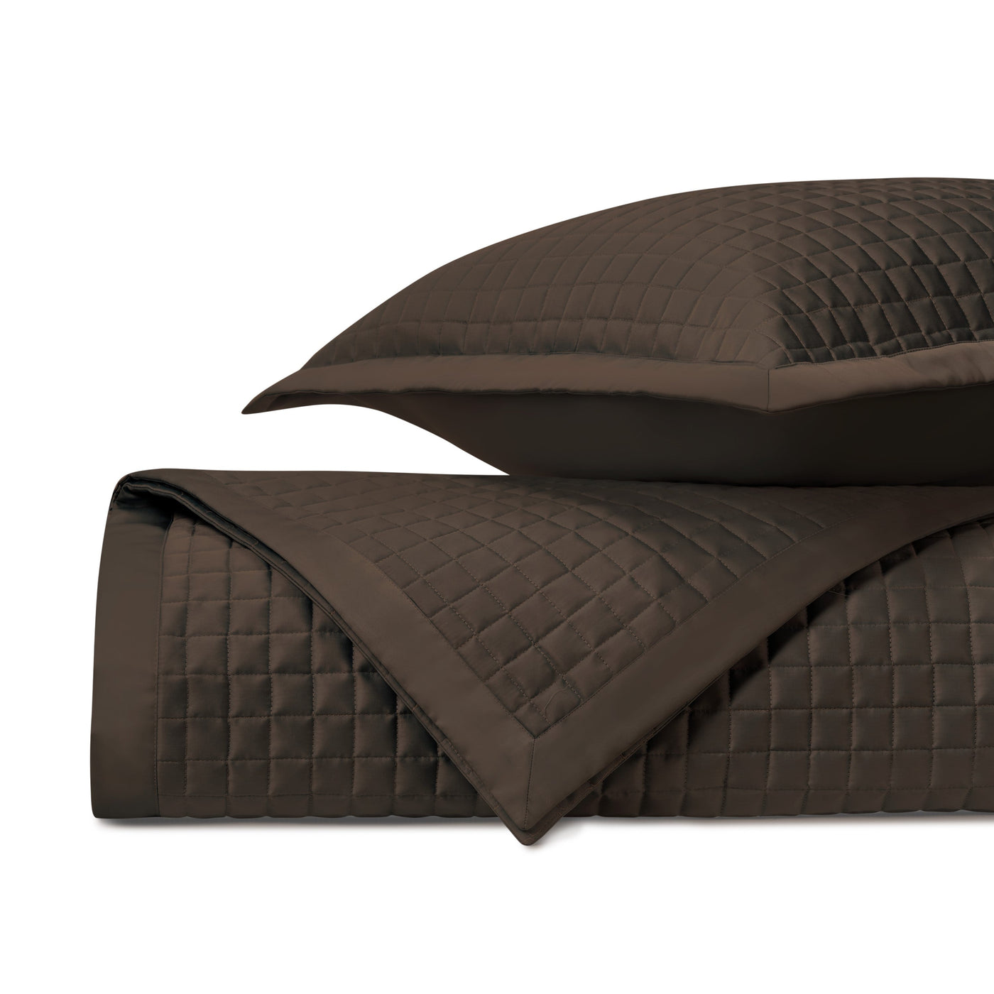 Chocolate quilted coverlet folded to show square stitching pattern and sham detail.