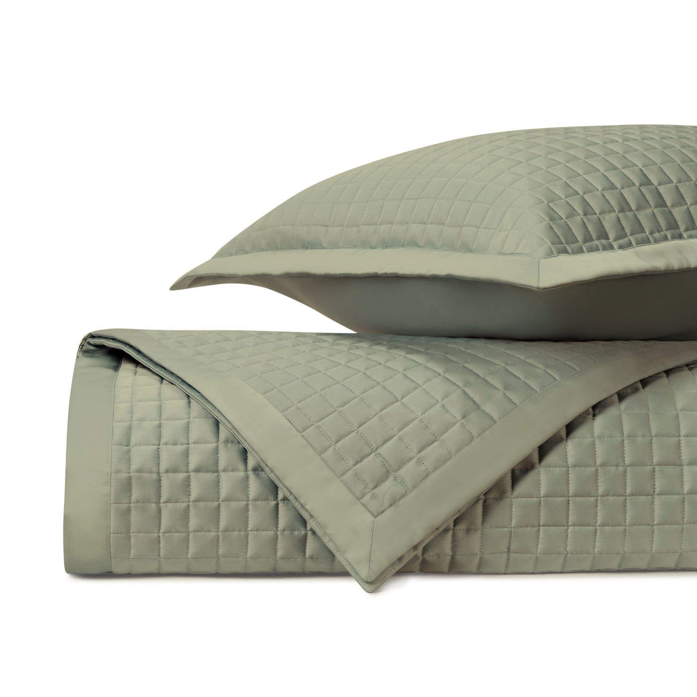Close-up of sage green quilted coverlet with geometric square stitching pattern and matching sham.