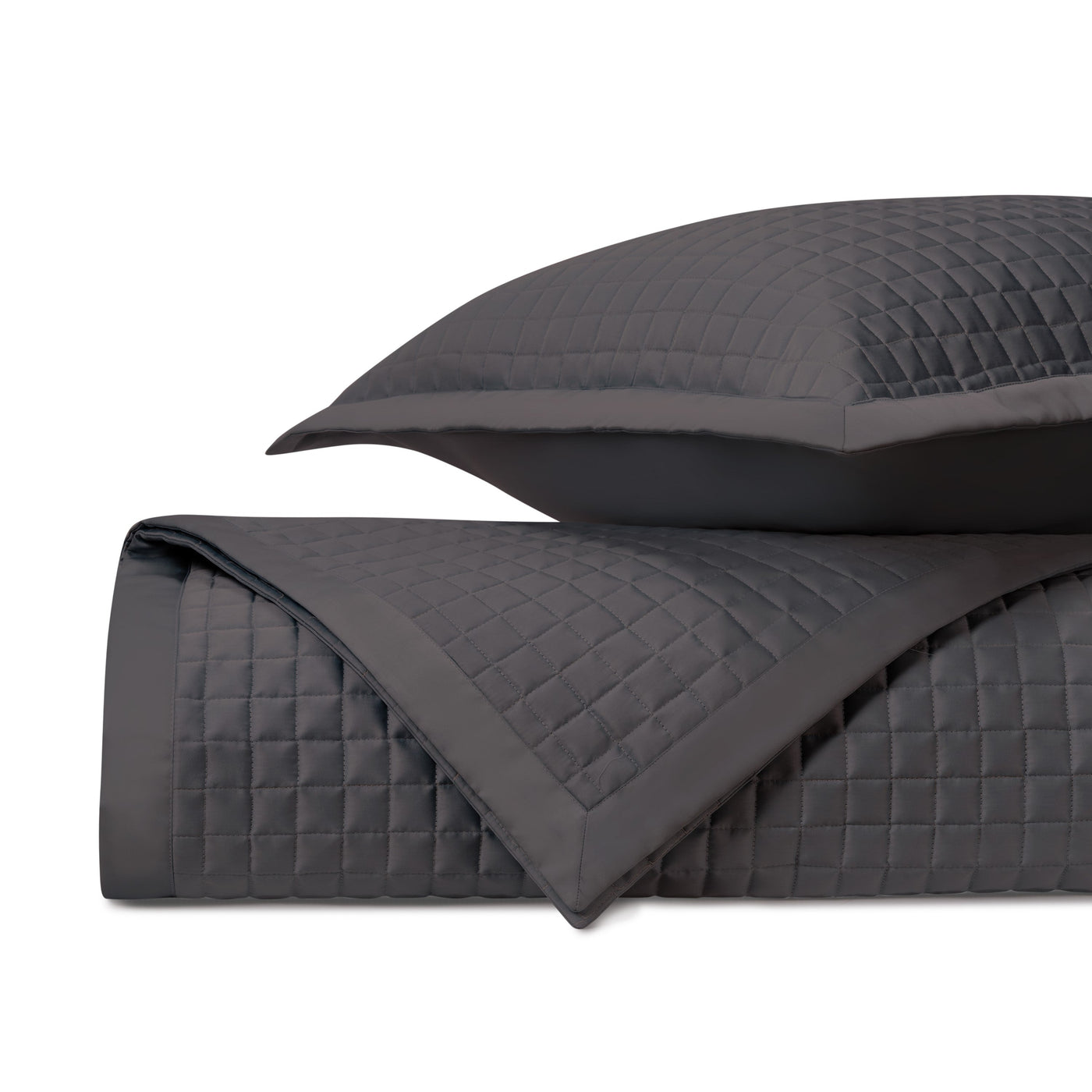 Charcoal quilted coverlet and sham folded to show diamond stitching pattern and border detail.