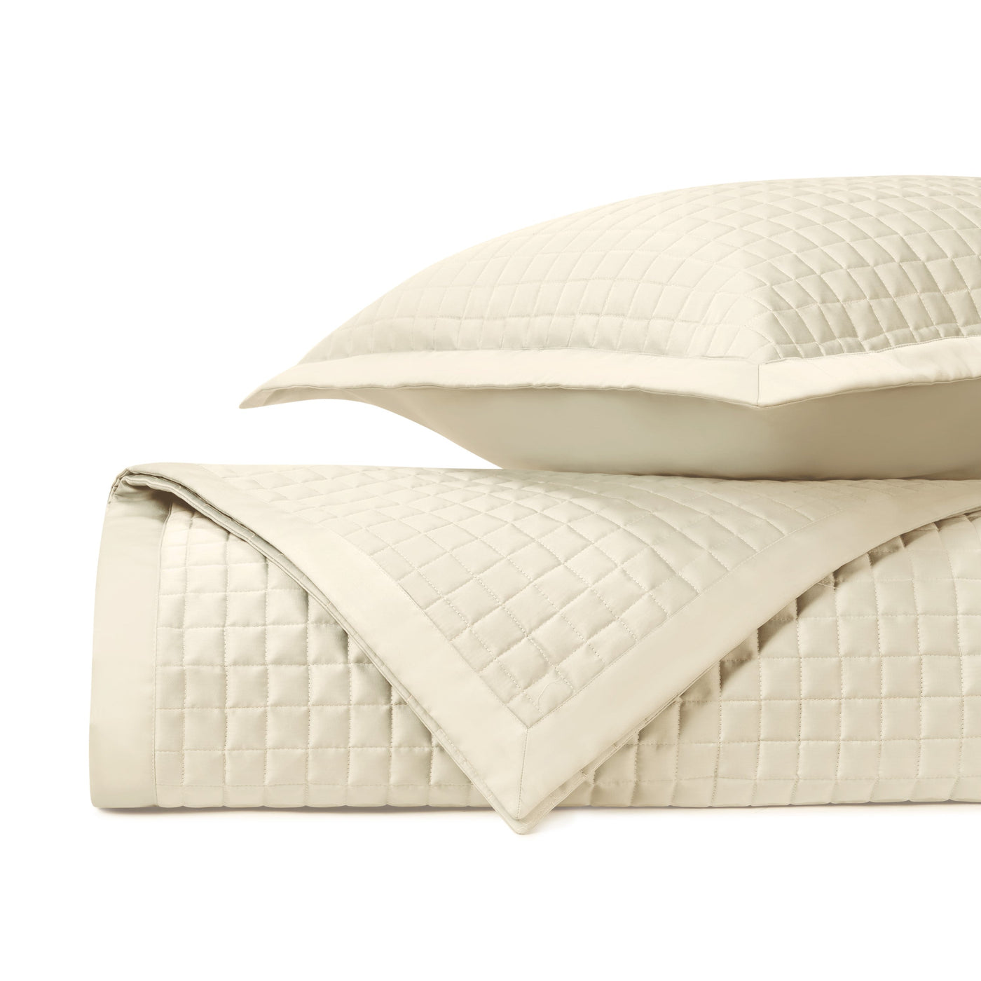 Close-up of ivory quilted coverlet and sham showing grid-stitched texture and border detail.