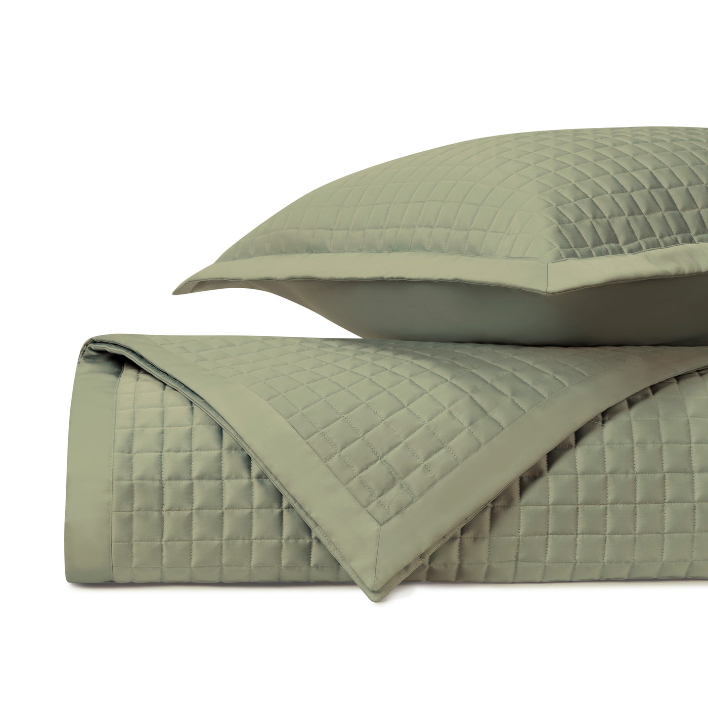 Close-up of sage green quilted coverlet showing geometric square stitching pattern and sham.