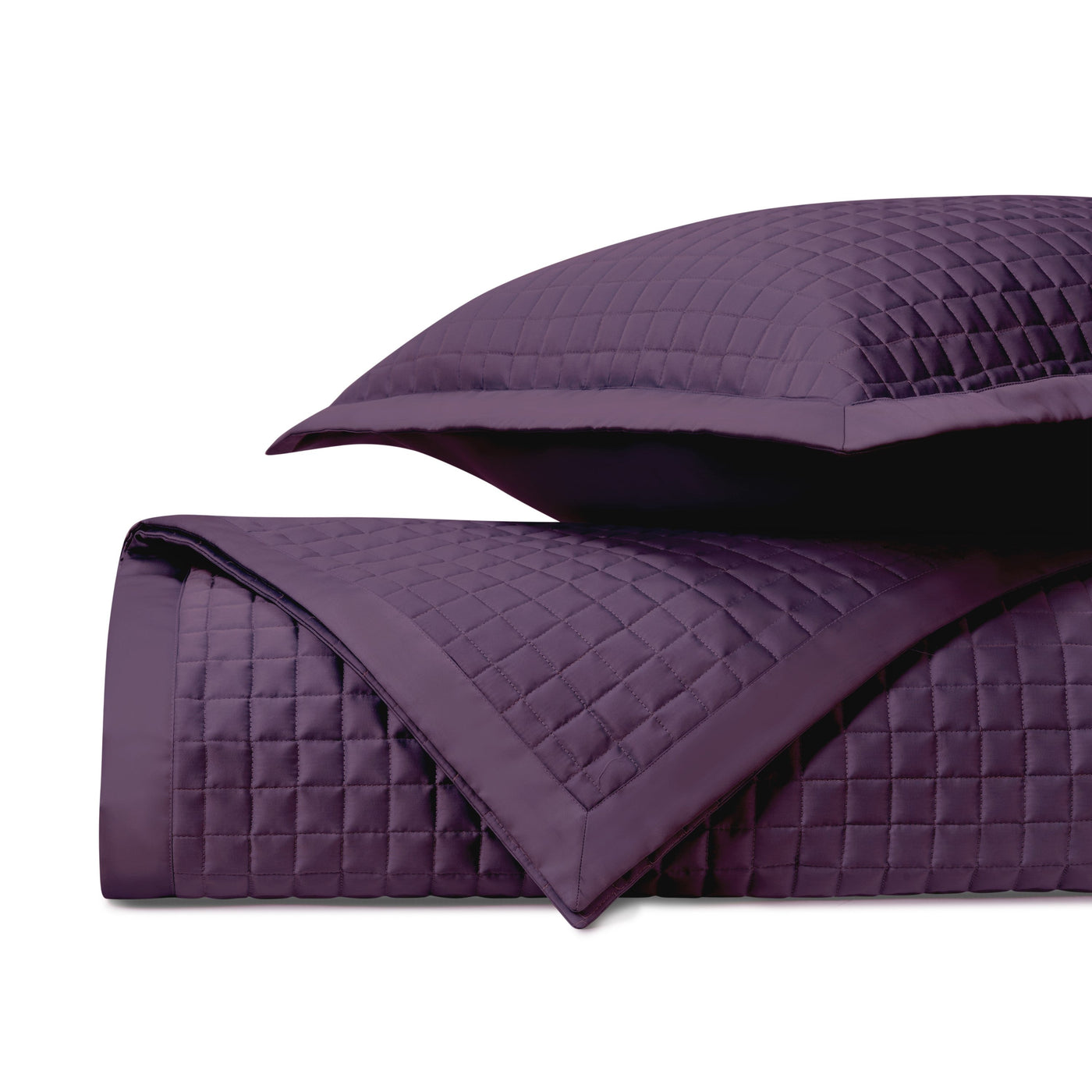 Close-up of amethyst quilted coverlet showing geometric diamond stitching pattern and satin border detail.