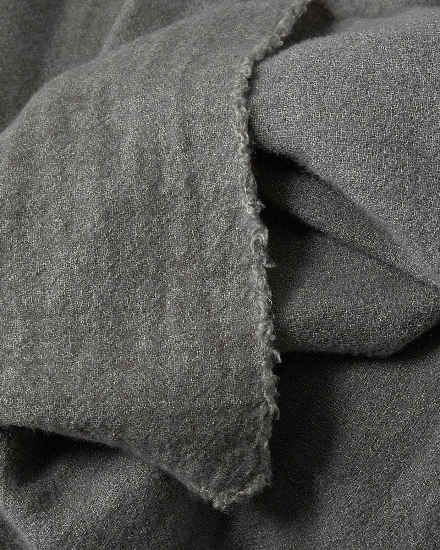 Close-up of Society Limonta Tiub throw's frayed linen edge in charcoal.