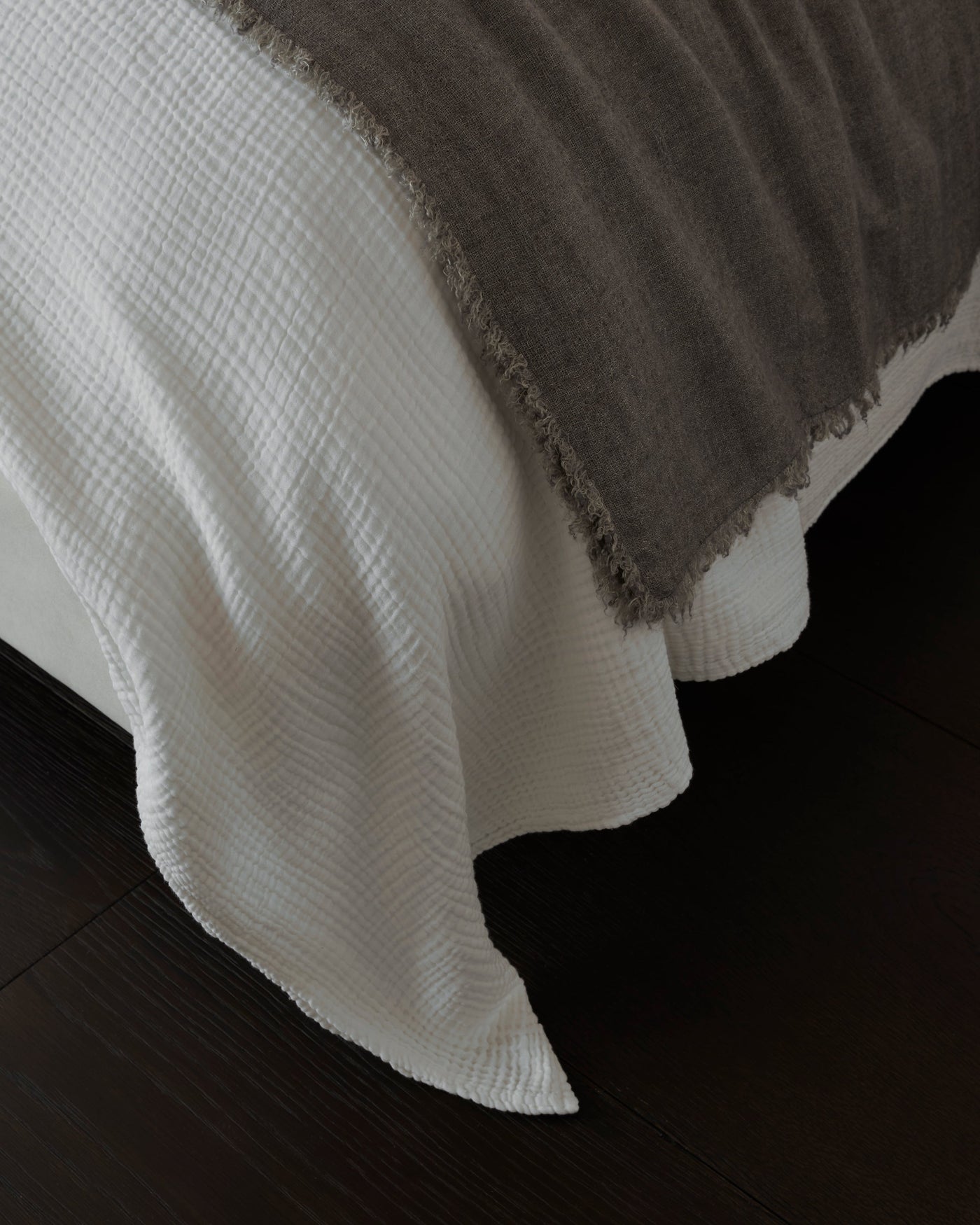 Close-up of ivory woven cotton throw draped over bed corner, showing textured weave.