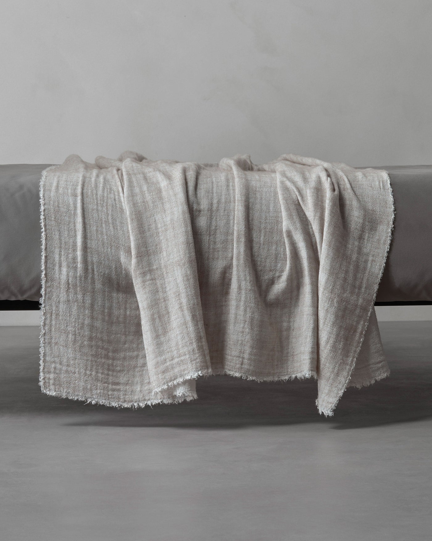 Society Limonta Tiub throw in ivory, draped over a charcoal bench showing frayed edges.