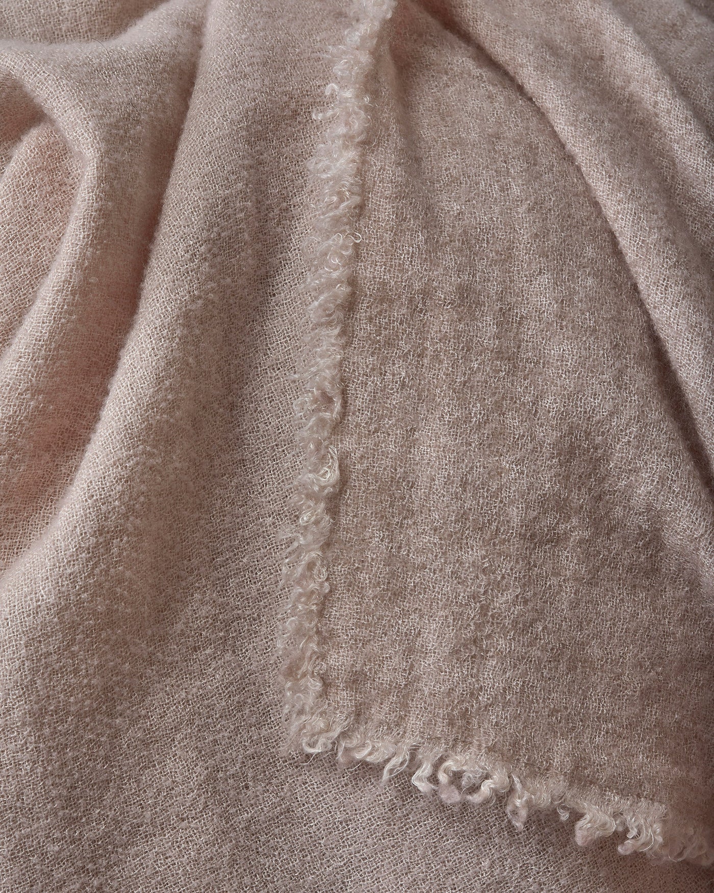 Close-up of Society Limonta Tiub throw's frayed edge seam in blush cashmere-soft fabric.