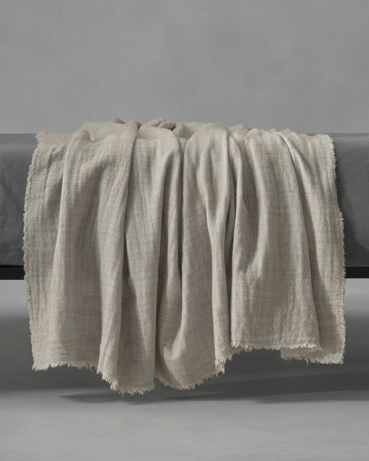Society Limonta Tiub throw in oatmeal woven linen with frayed edges draped over bench.