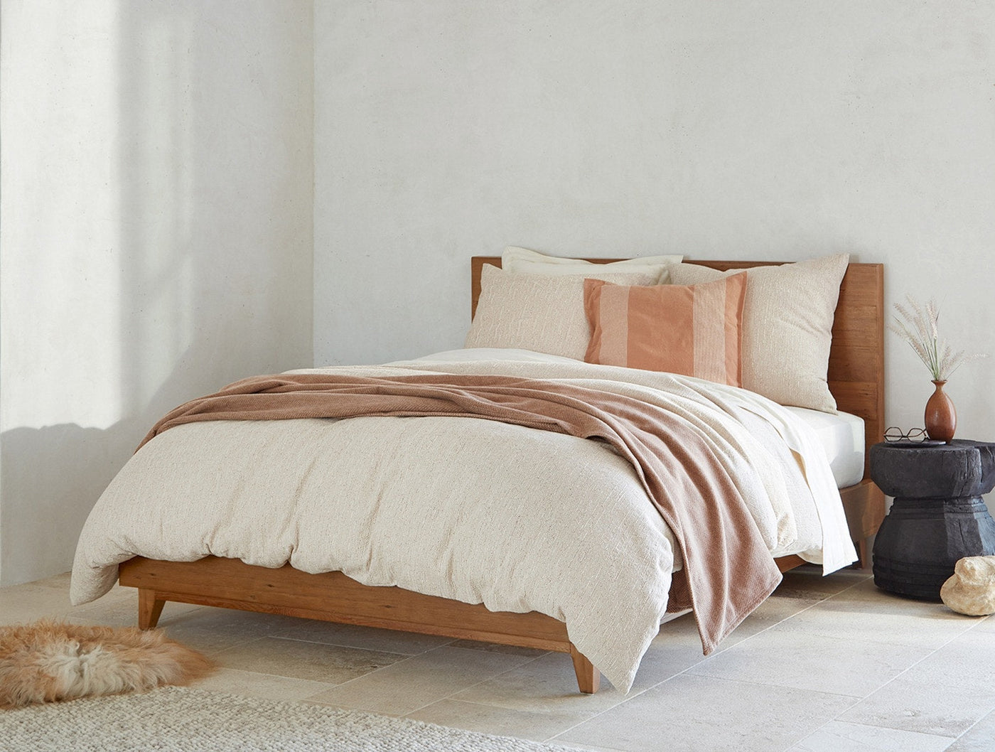 Ivory textured duvet cover styled on bed with terracotta throw and mixed accent pillows.