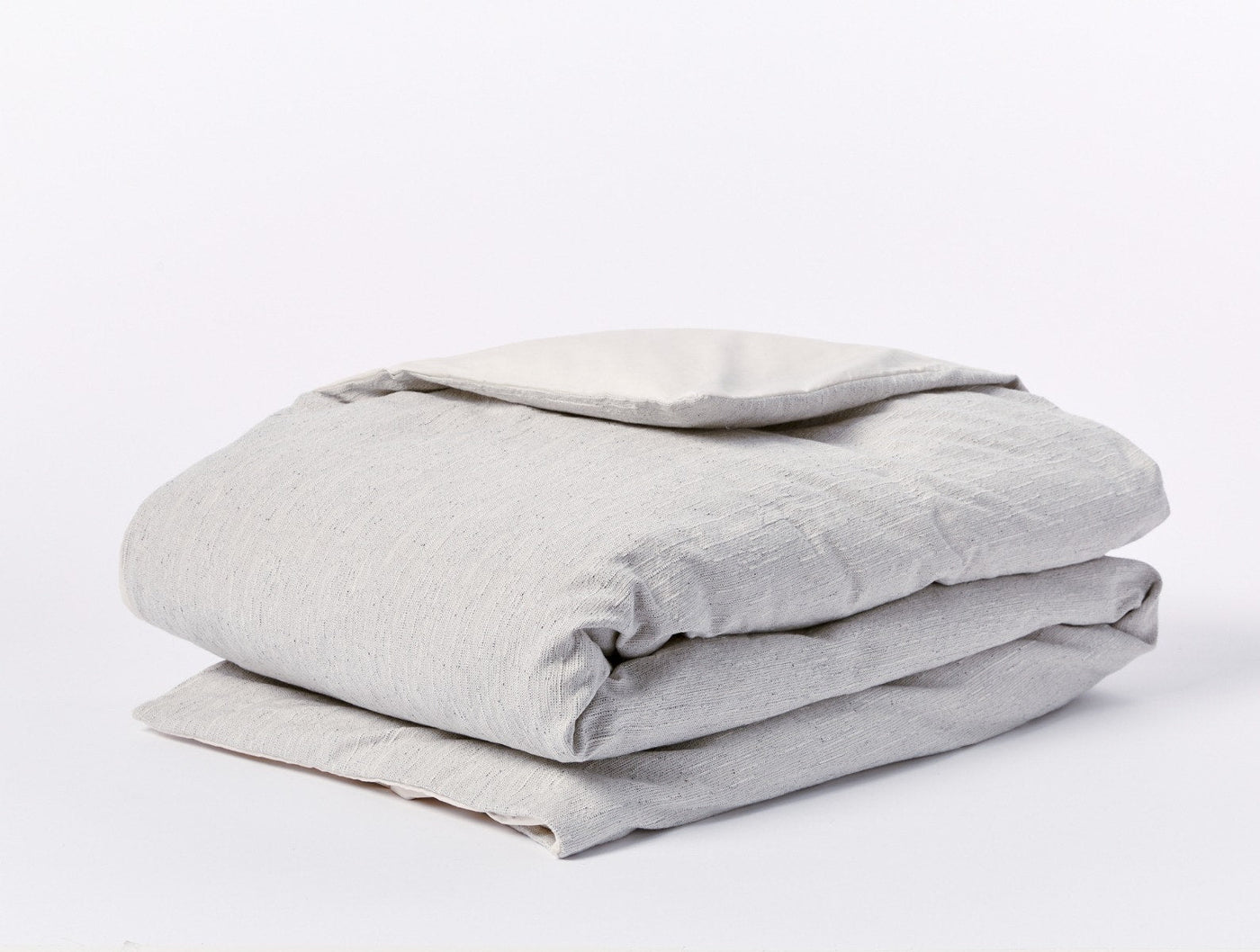 Folded dove grey linen duvet cover with natural reverse, showing textured weave.