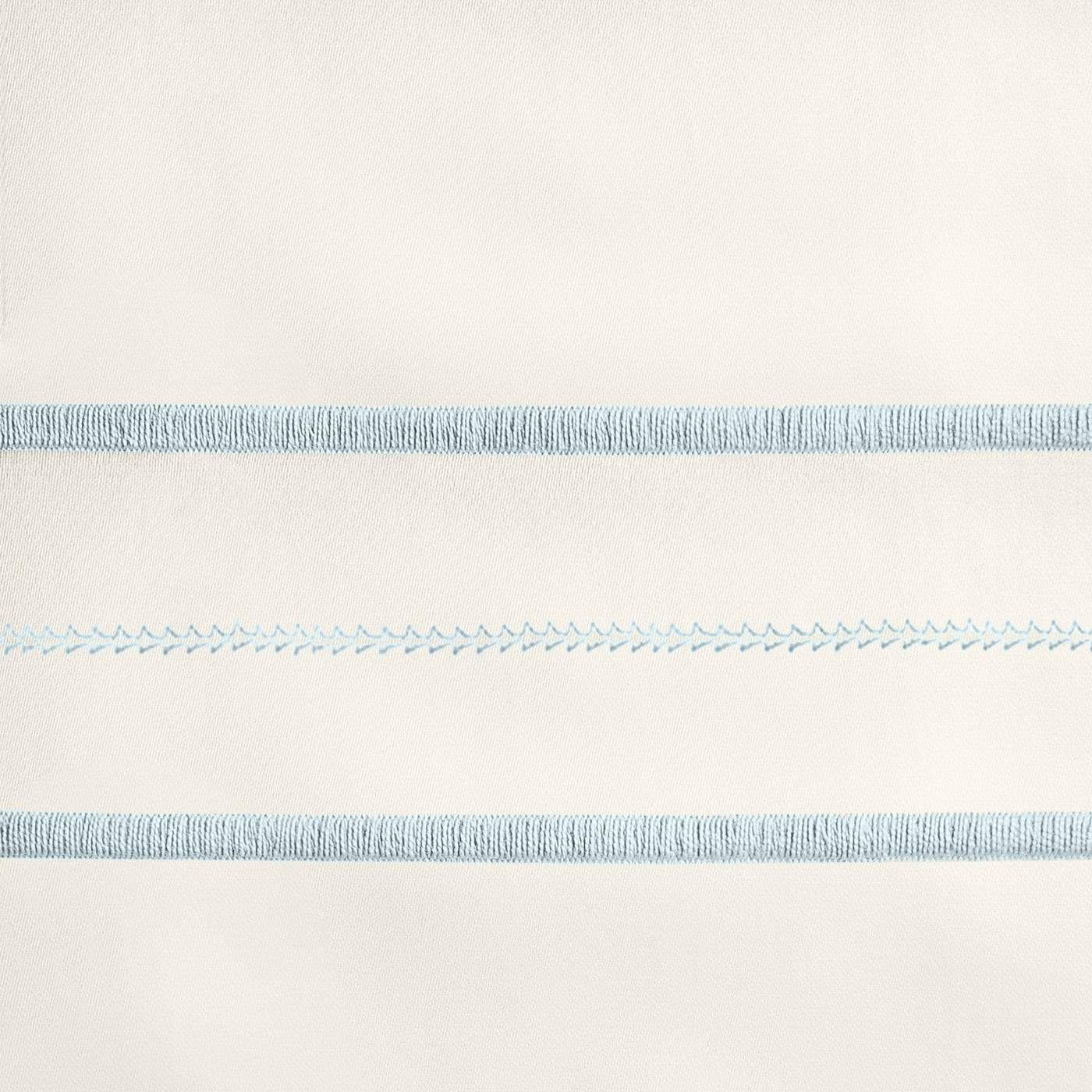Close-up of sky blue embroidered stripe detail on ivory cotton flat sheet.