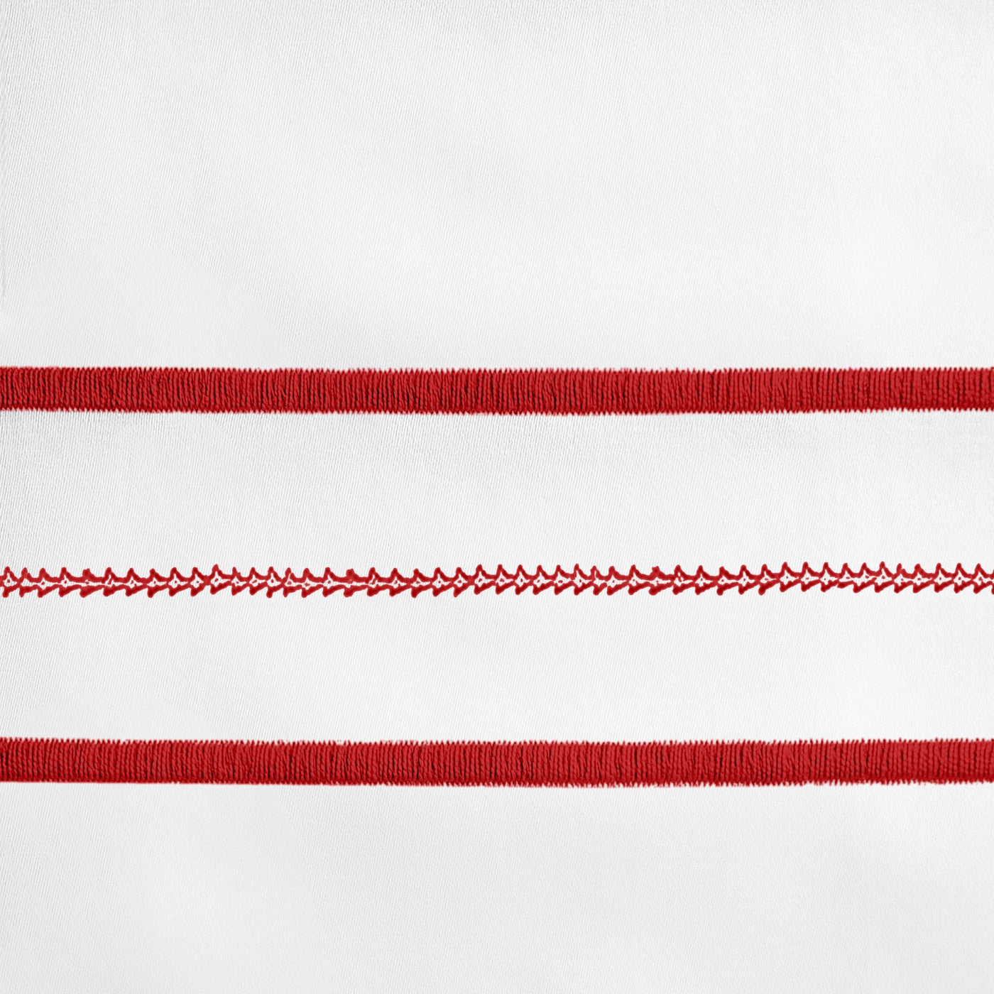 Close-up of crimson embroidered stripe detail on white linen pillowcase.
