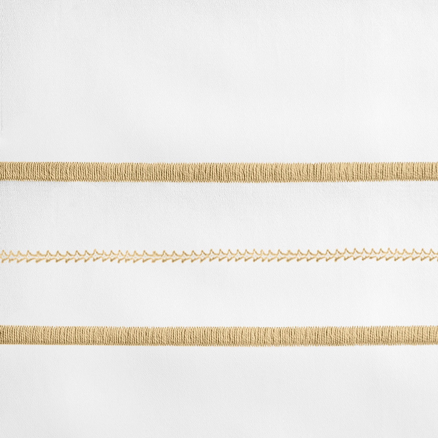 Close-up of gold embroidered stripe detail on white linen, showing textured braid and chevron stitching.