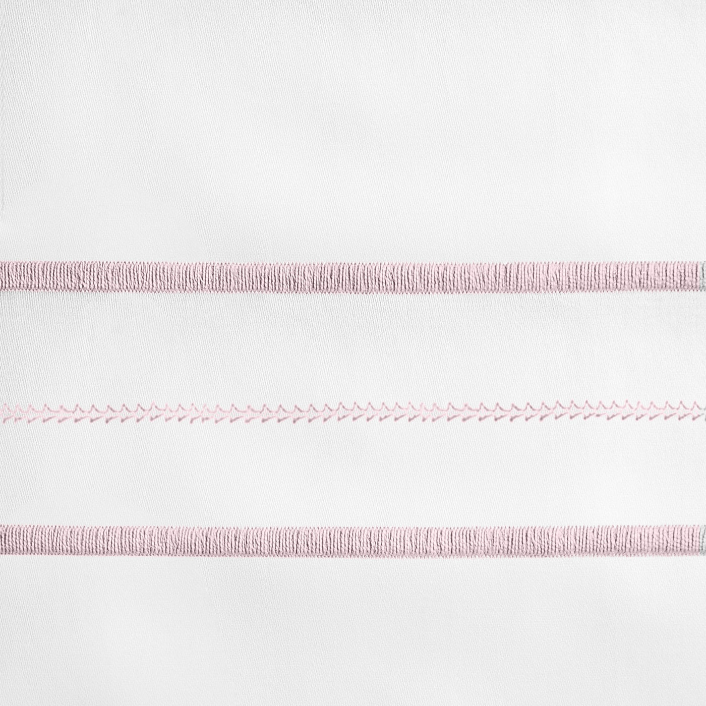 Close-up of blush embroidered stripe detail on white linen pillow sham.