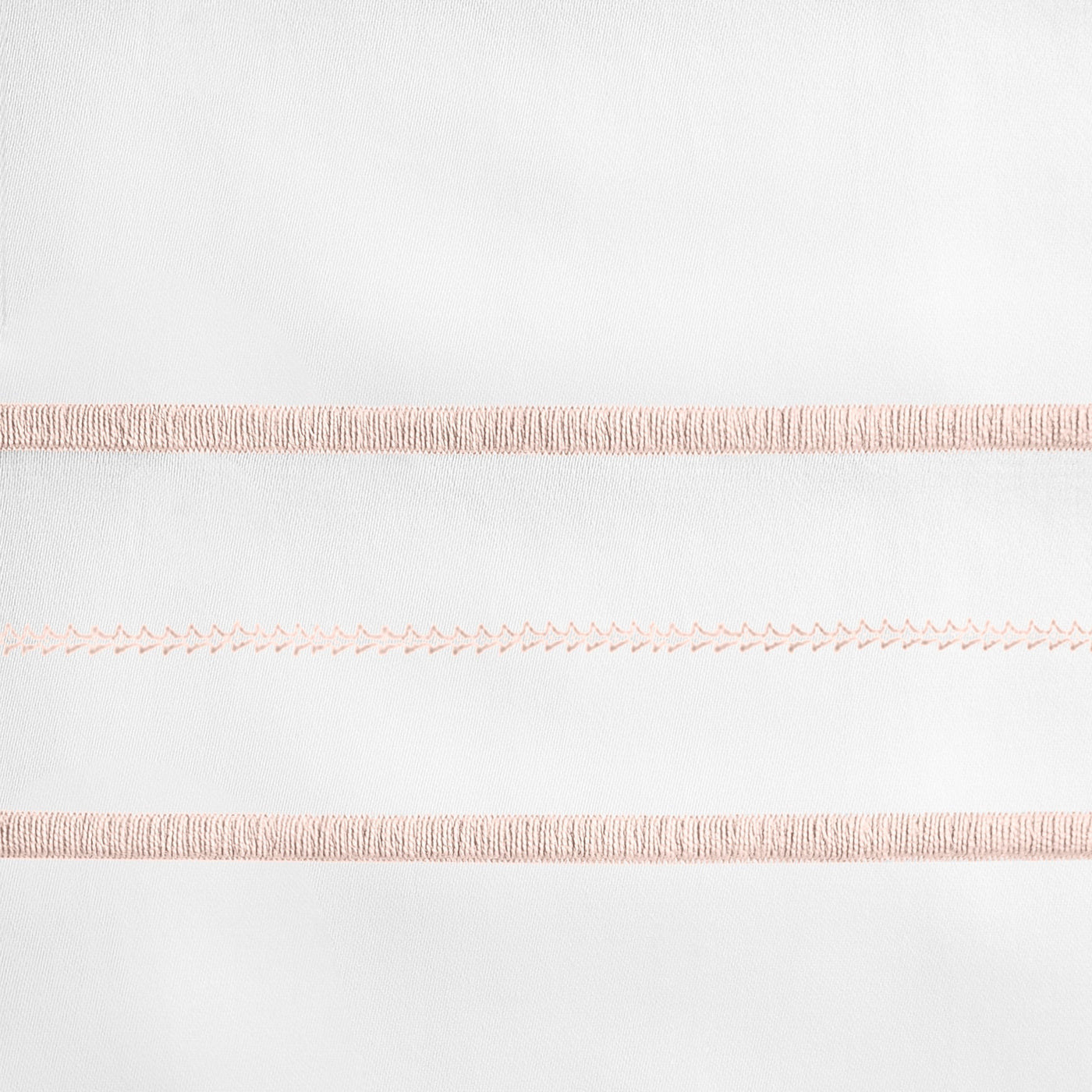 Close-up of blush embroidered stripe detail on white linen pillow sham.