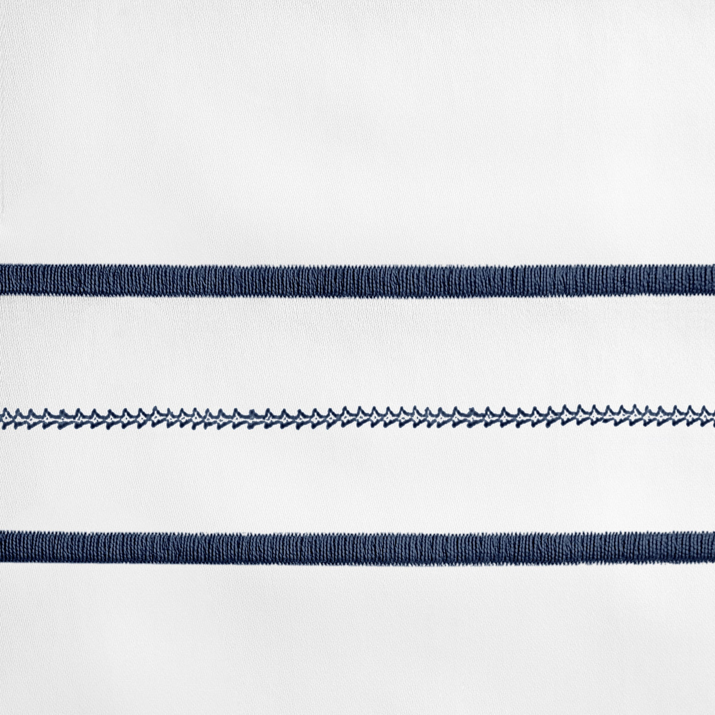 Close-up of navy embroidered stripe detail on white linen, showing contrast stitching texture.