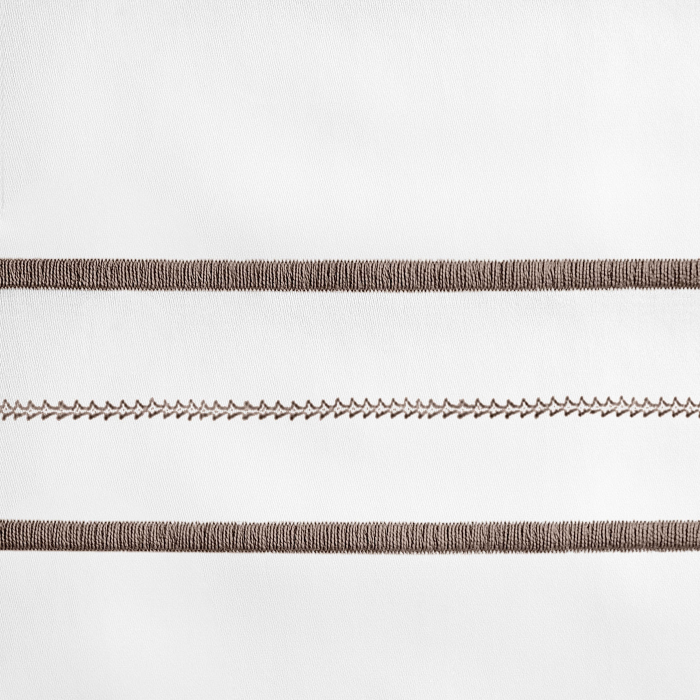 Close-up of mocha embroidered stripe detail on white linen flat sheet.