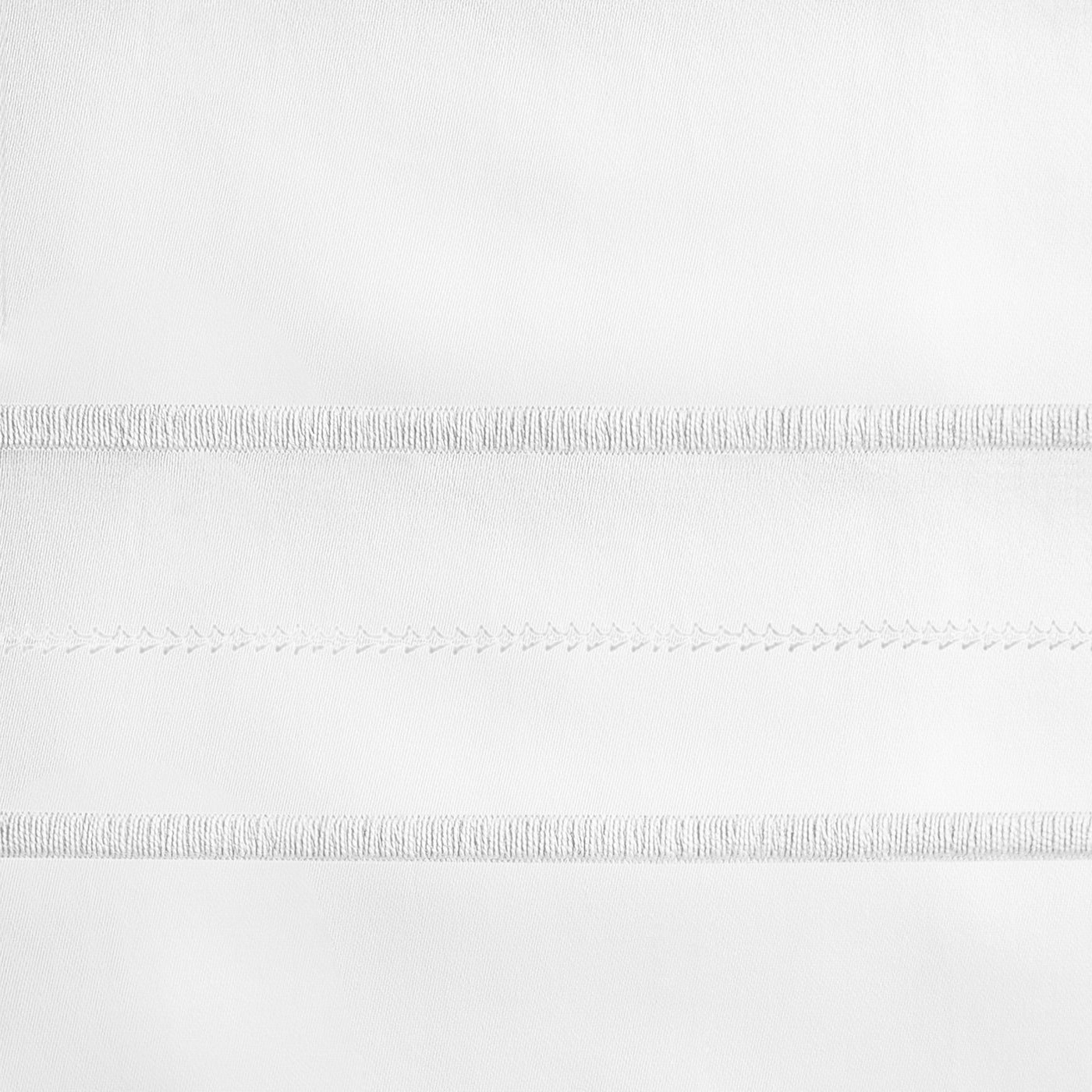 Close-up of white-on-white embroidered horizontal bands on fine linen fabric.
