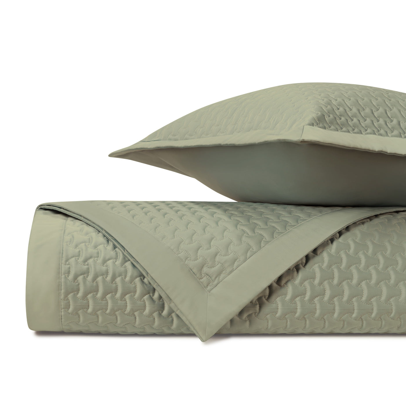 Sage green quilted texture detail on folded coverlet and sham.