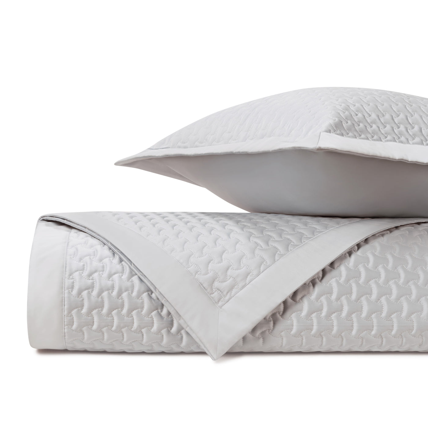 Close-up of Trinity quilted coverlet in pale silver with geometric link pattern.