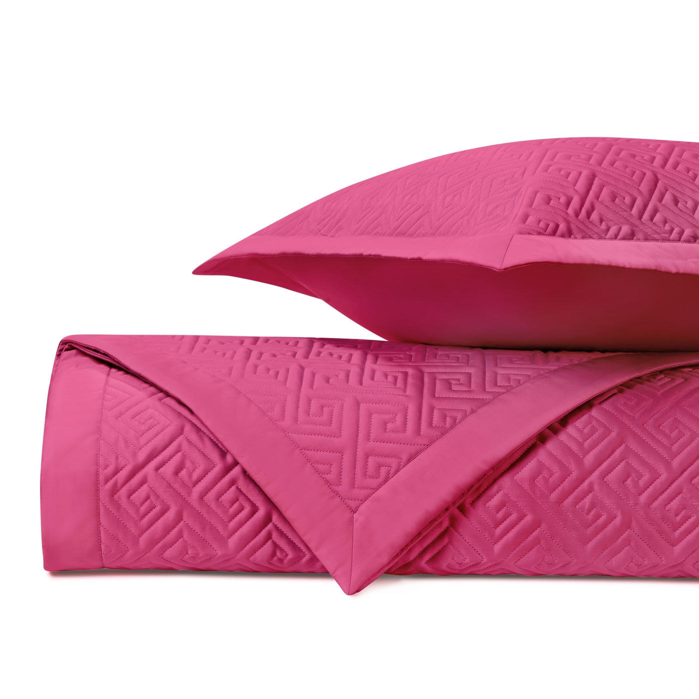 Close-up of fuchsia quilted coverlet with tone-on-tone Greek key pattern, folded with matching sham.