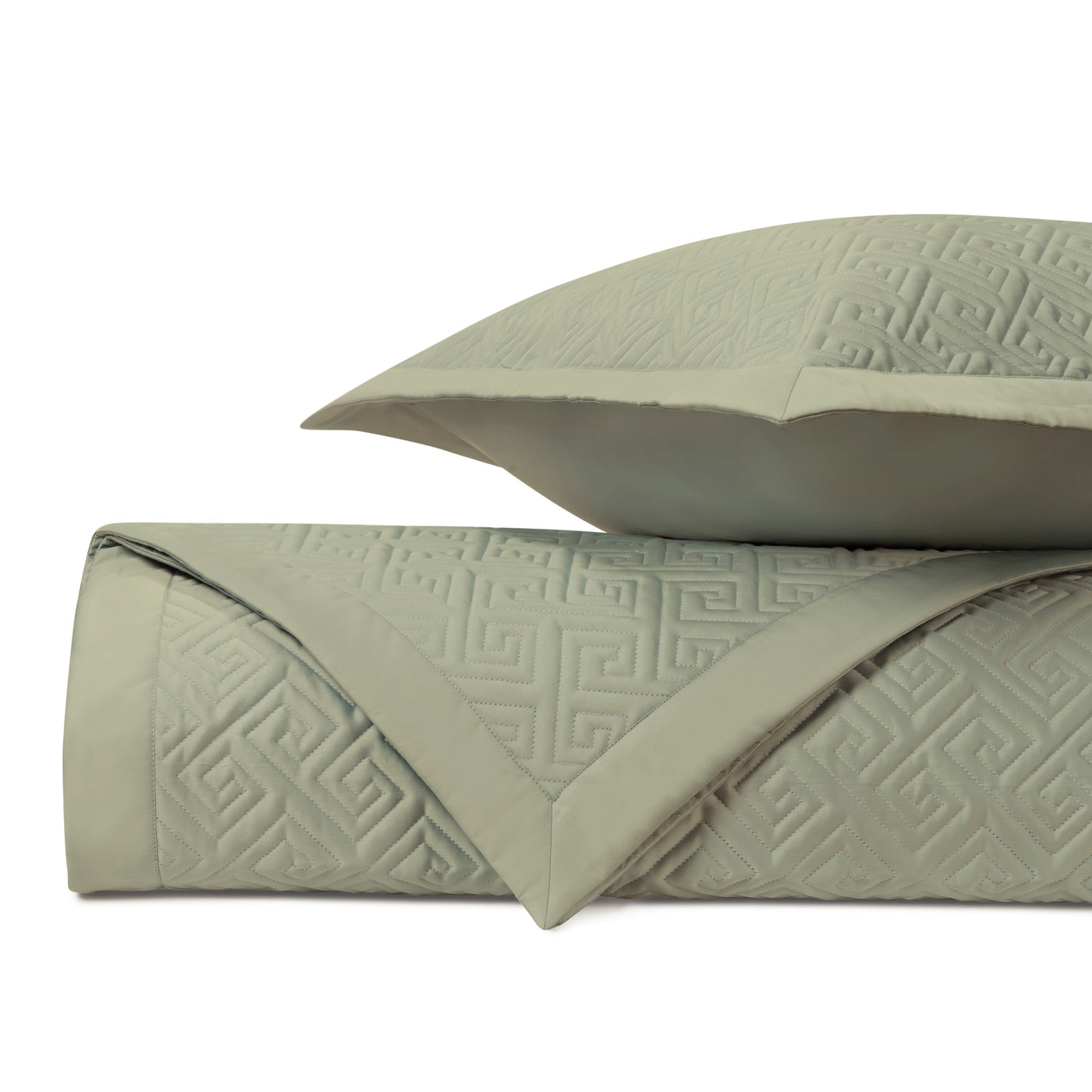 Sage green quilted coverlet folded with sham, Greek key pattern in tone-on-tone relief.