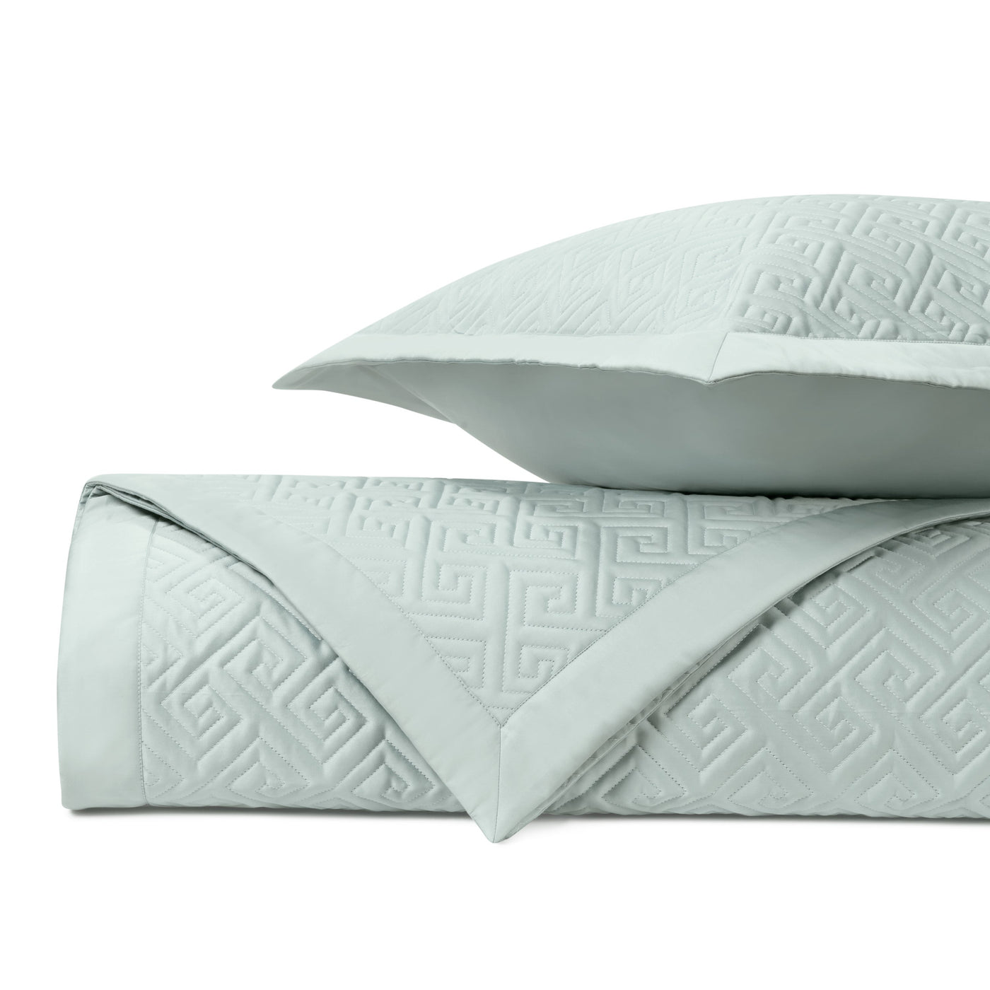 Folded mist quilted coverlet with Greek key pattern alongside matching euro sham.