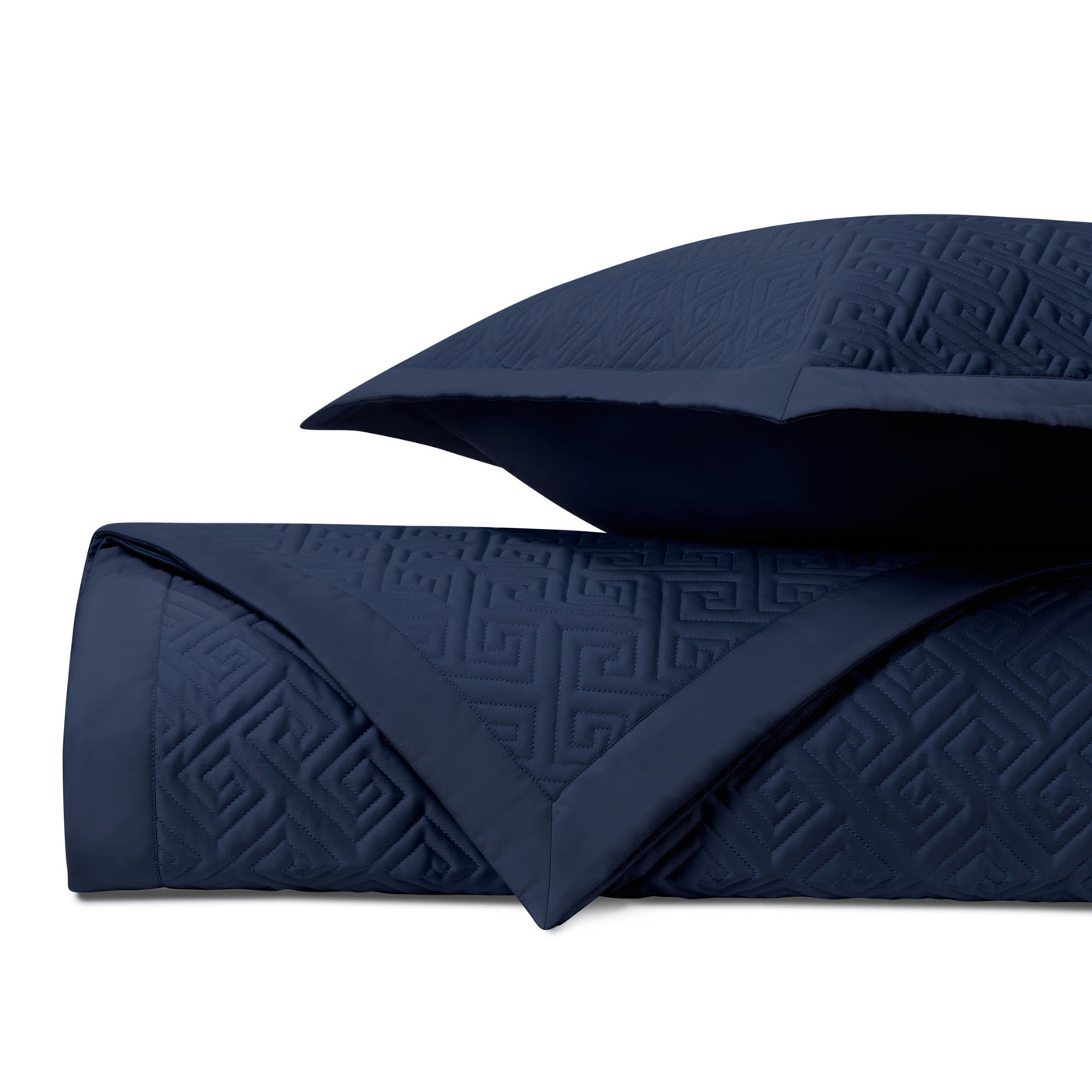 Close-up of navy quilted coverlet with tonal Greek key embossed pattern and matching euro sham.