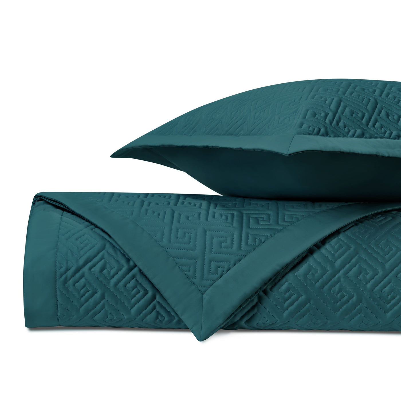 Close-up of teal quilted coverlet with embossed Greek key pattern, folded with matching euro sham.