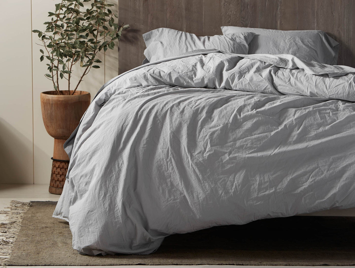Soft grey Coyuchi Crinkled Percale duvet styled on a bed with natural wood headboard.