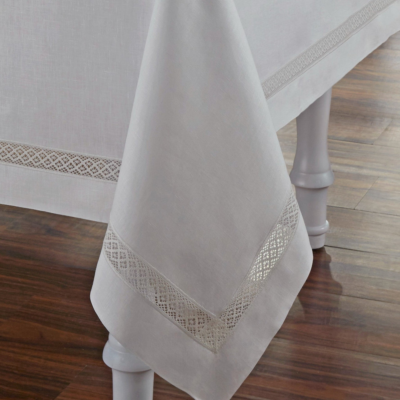 Corner detail of Home Treasures Valencia tablecloth in ivory with geometric lace border trim.