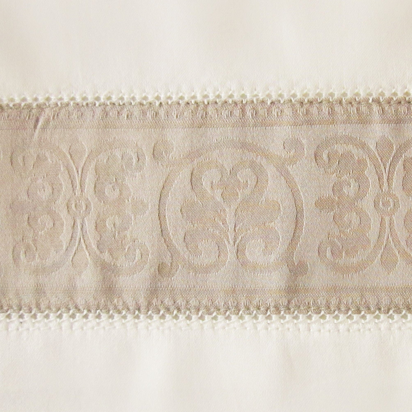 Close-up of Venice flat sheet's woven medallion border trim in champagne linen.