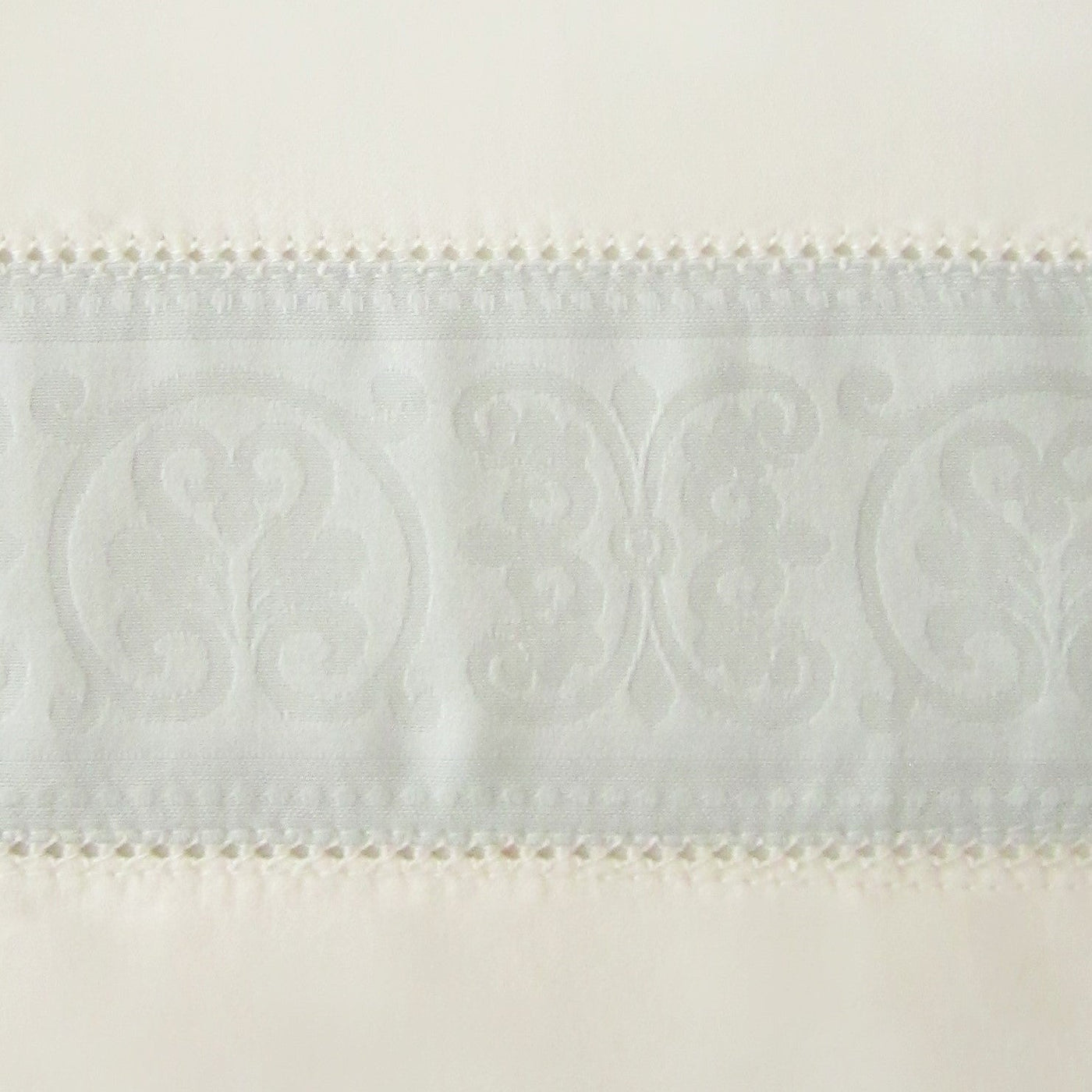 Close-up of Venice flat sheet ivory border with woven damask medallion and lace trim detail.