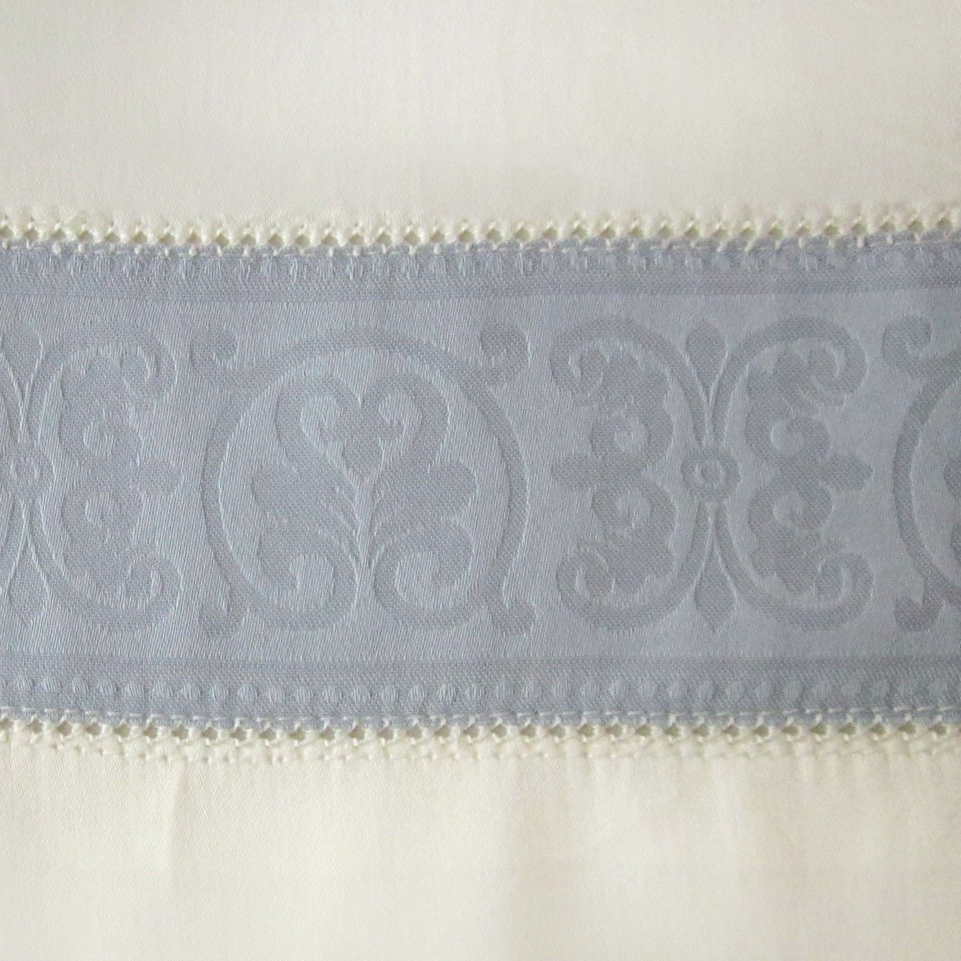 Close-up of slate blue jacquard medallion border with ivory crochet trim detail.