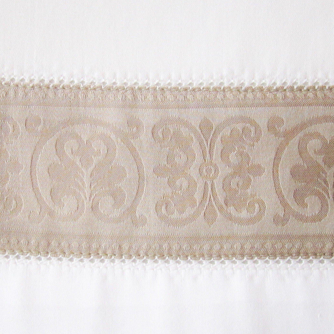 Close-up of Venice pillowcase's champagne jacquard medallion border on white cotton.