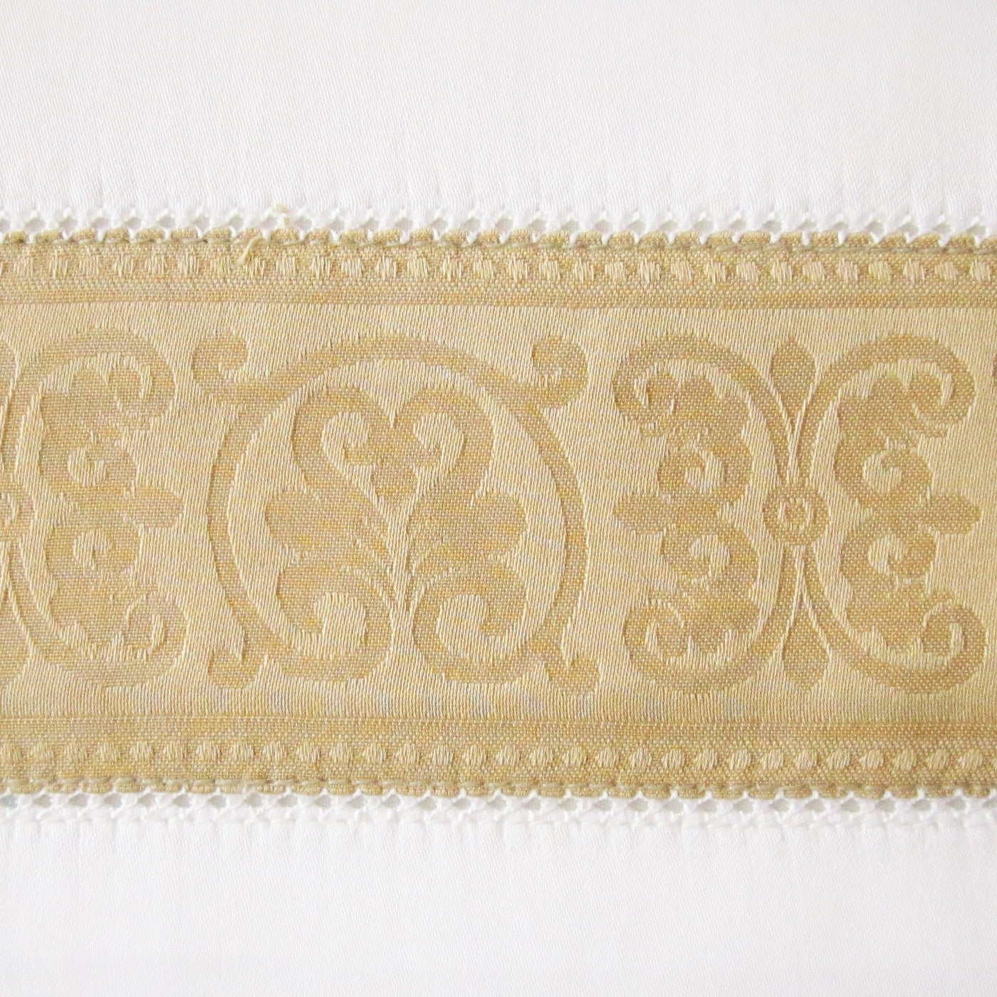 Close-up of champagne woven jacquard border trim with ornate scroll medallion pattern.